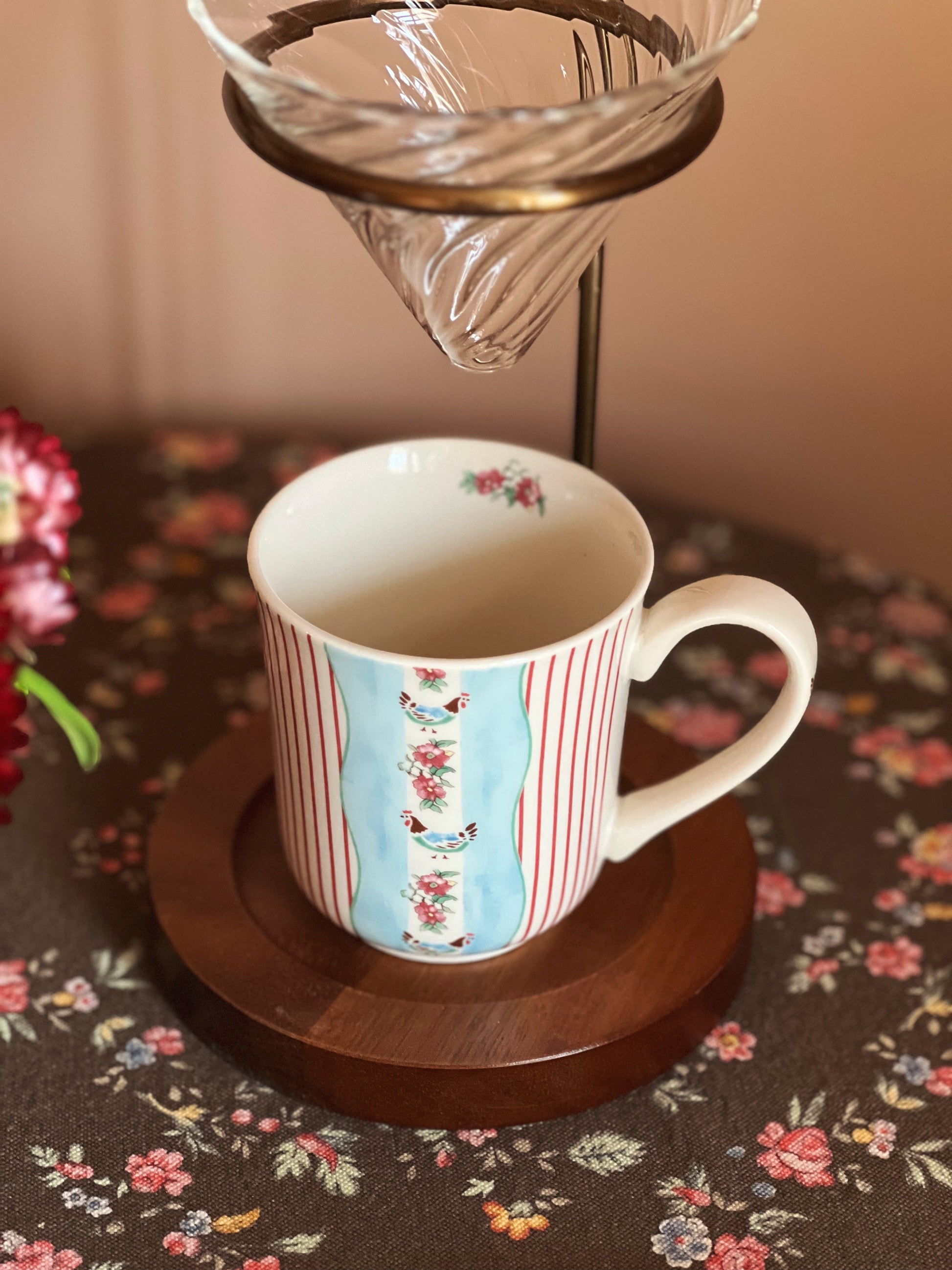 Decorative coffee cup with floral pattern on a wooden coaster
