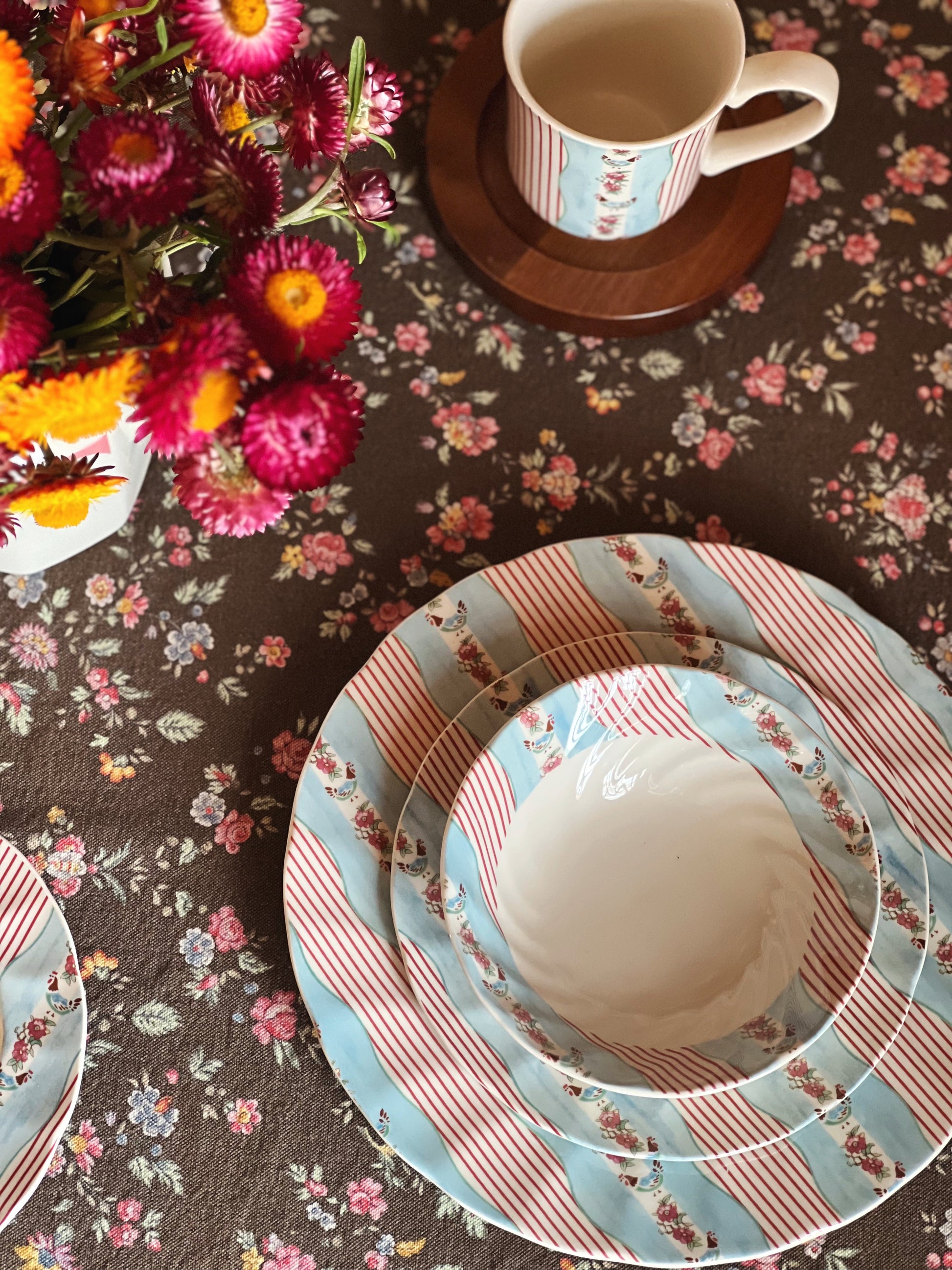 Decorative table setting with floral tablecloth, patterned plates, and a cup.