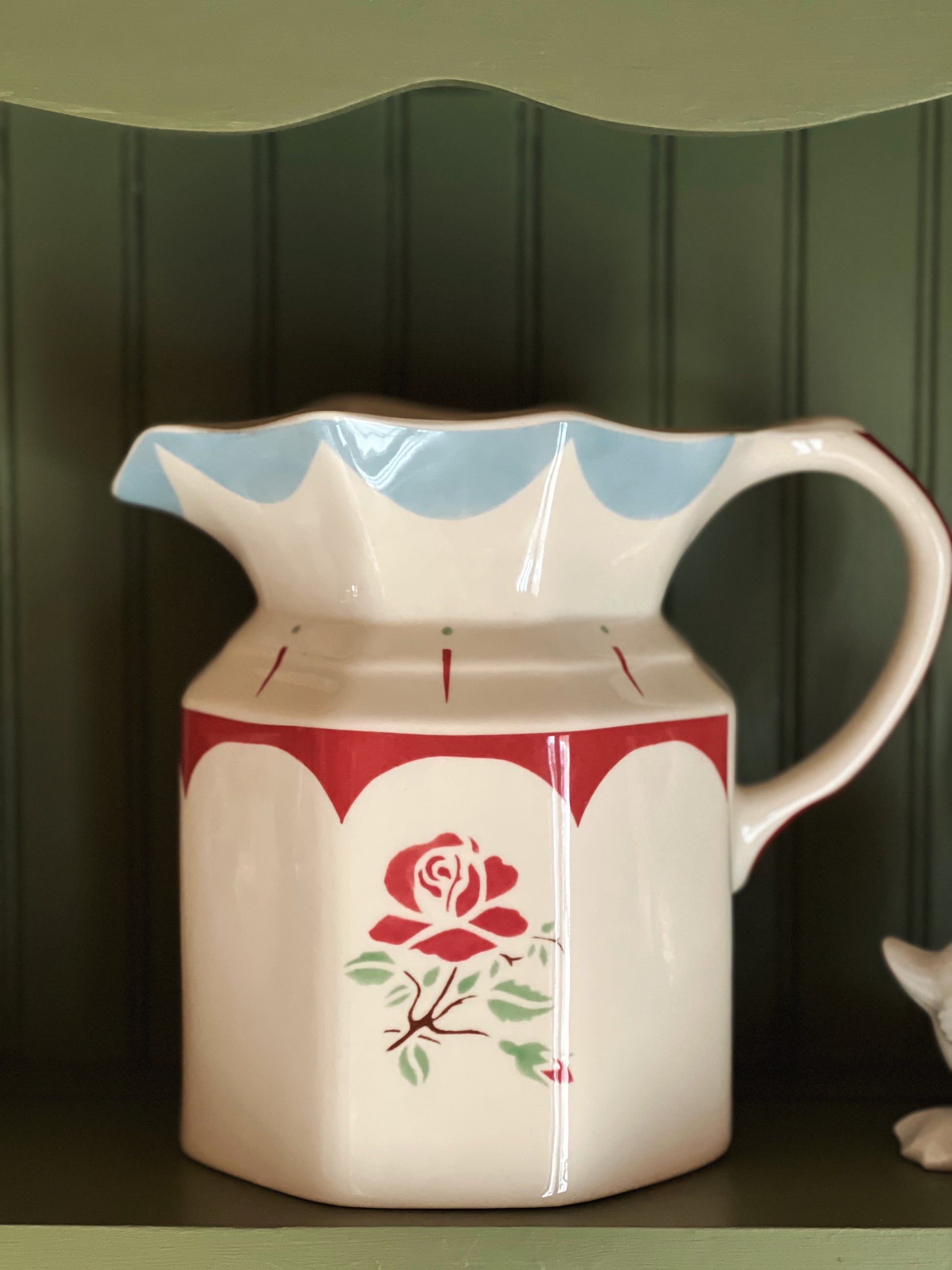 Ceramic pitcher with a red rose design on a green background