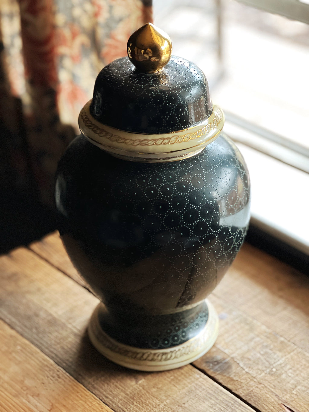 Decorative black urn with gold lid on a wooden surface