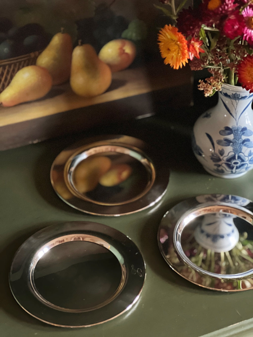 Decorative table setting with metallic coasters, pears, and a vase.