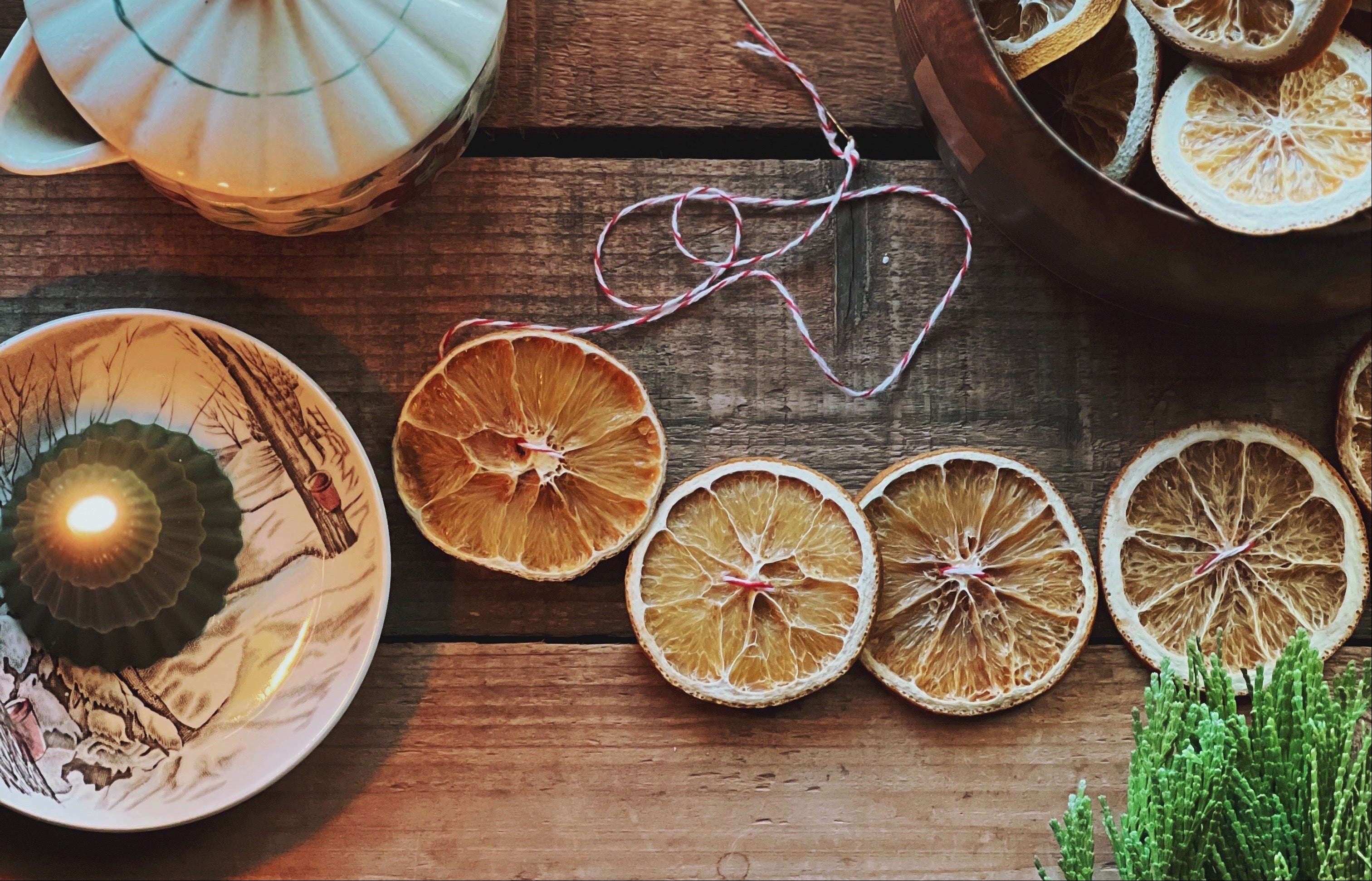 Tea set with dried citrus slices and candles on a wooden surface