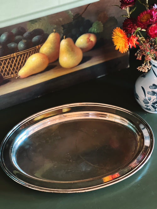 Silver tray on a table with fruit and flowers in the background