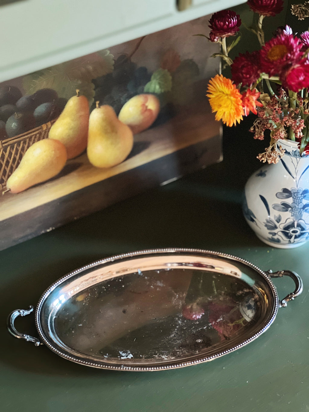 Decorative still life with pears, flowers, and a silver tray on a table.