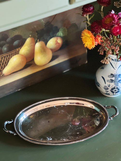 Decorative still life with pears, flowers, and a silver tray on a table.