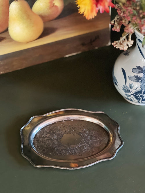 Silver decorative tray on a dark surface with pears and flowers in the background