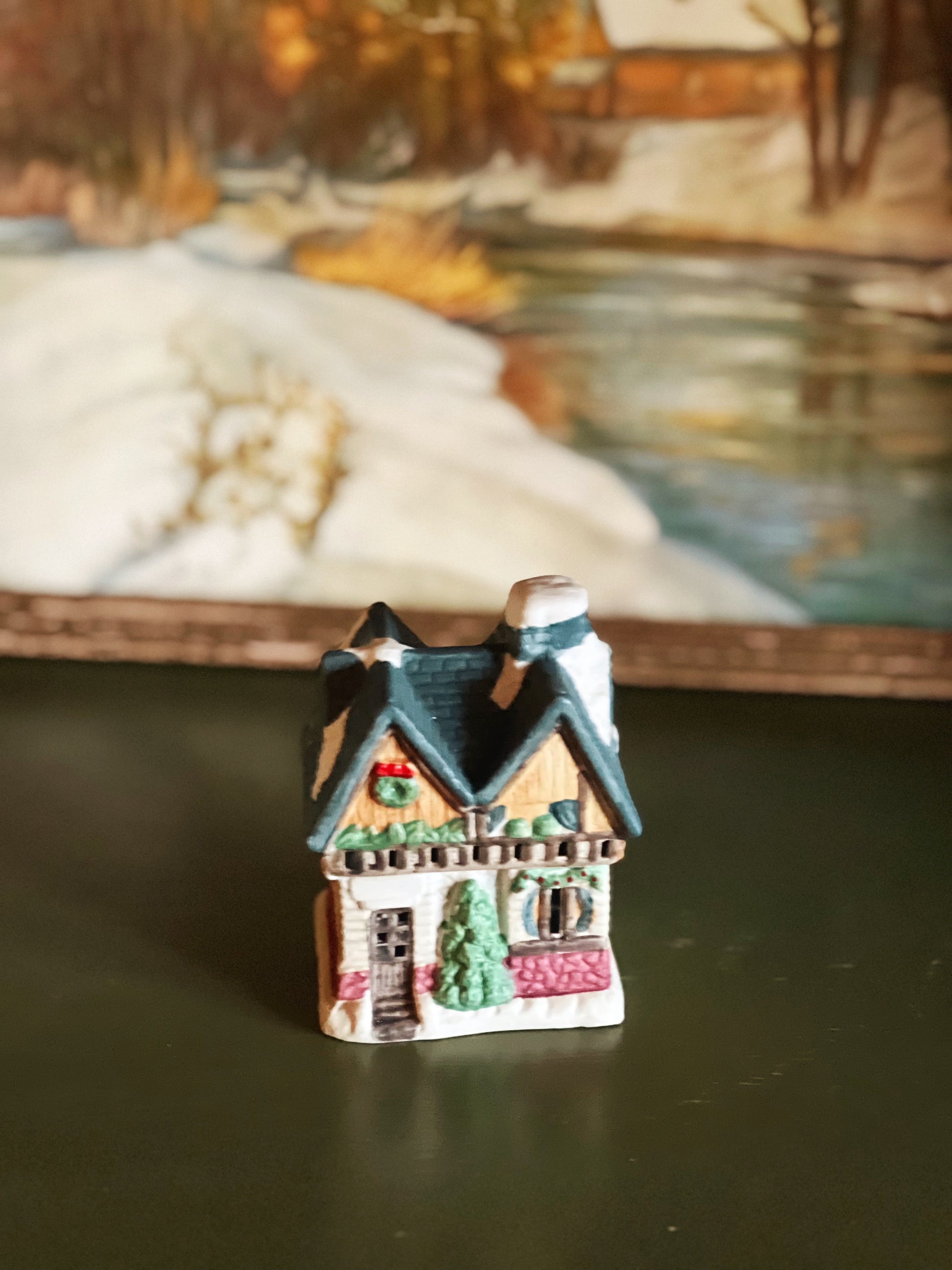 Small decorative house figurine on a reflective surface with a blurred natural background
