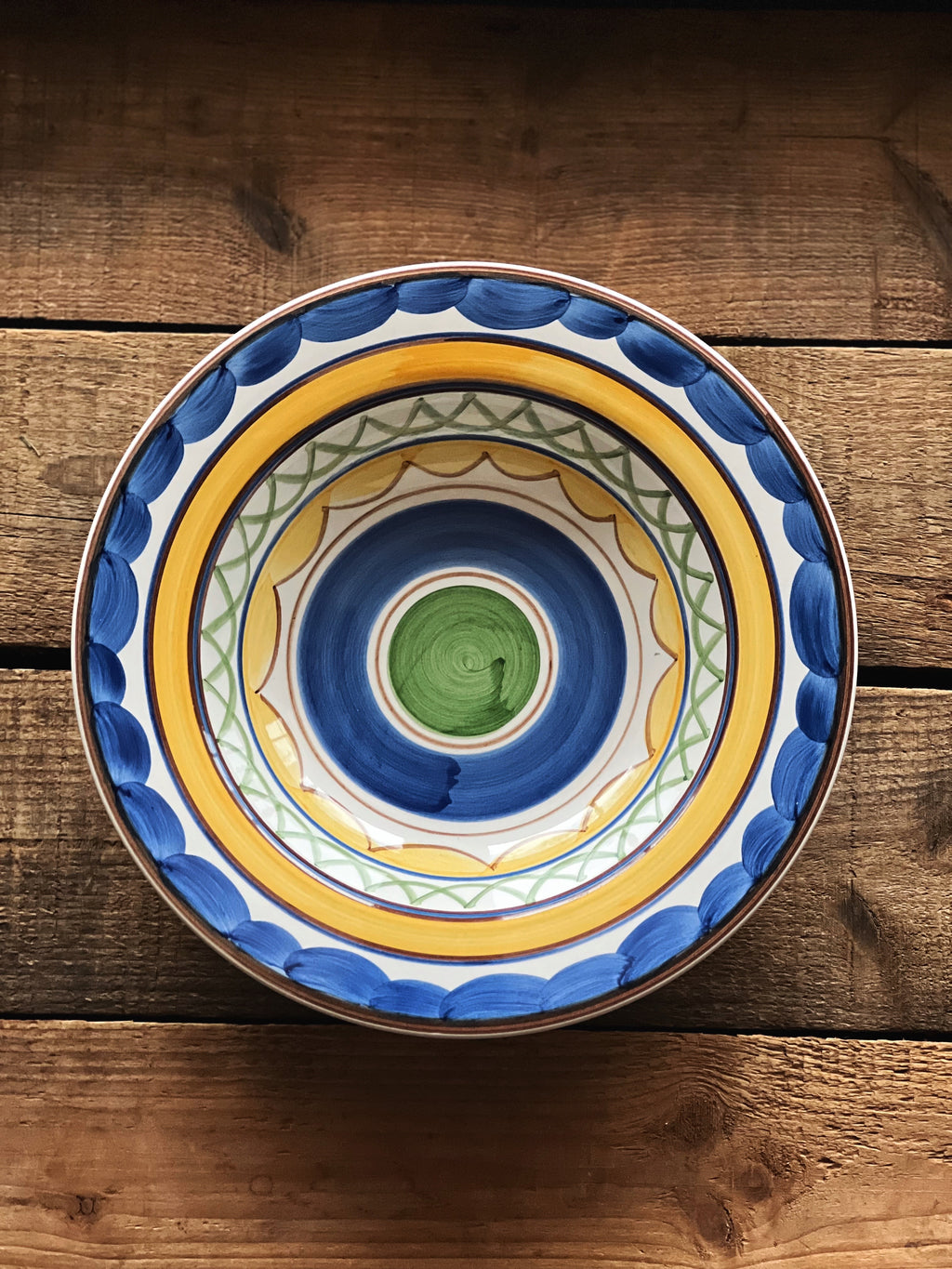 Decorative ceramic plate with blue and yellow patterns on a wooden surface