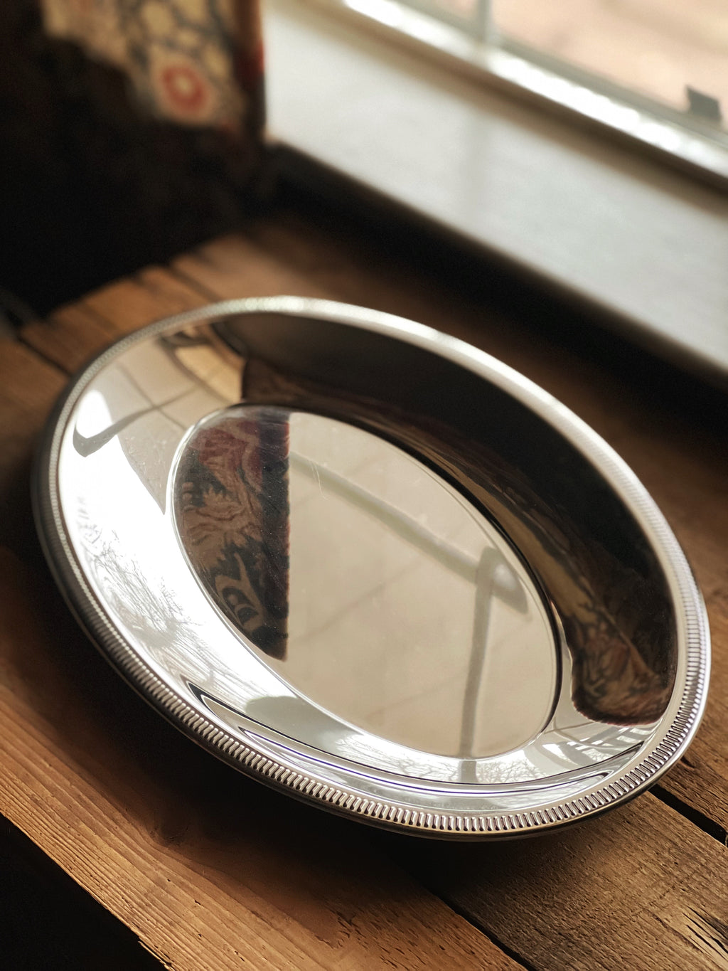 Silver oval tray on a wooden surface with a blurred background
