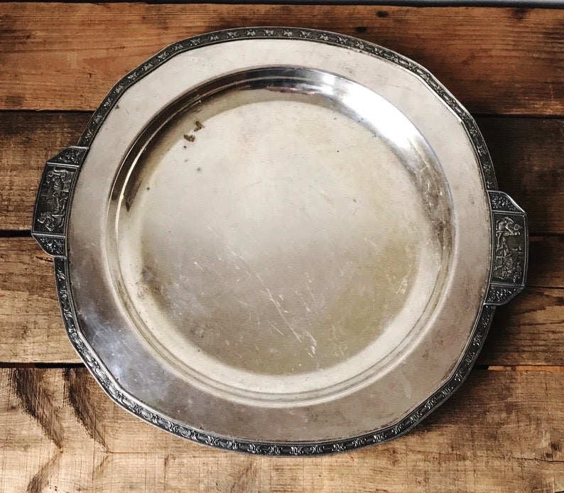 Silver tray with decorative edge on a wooden surface