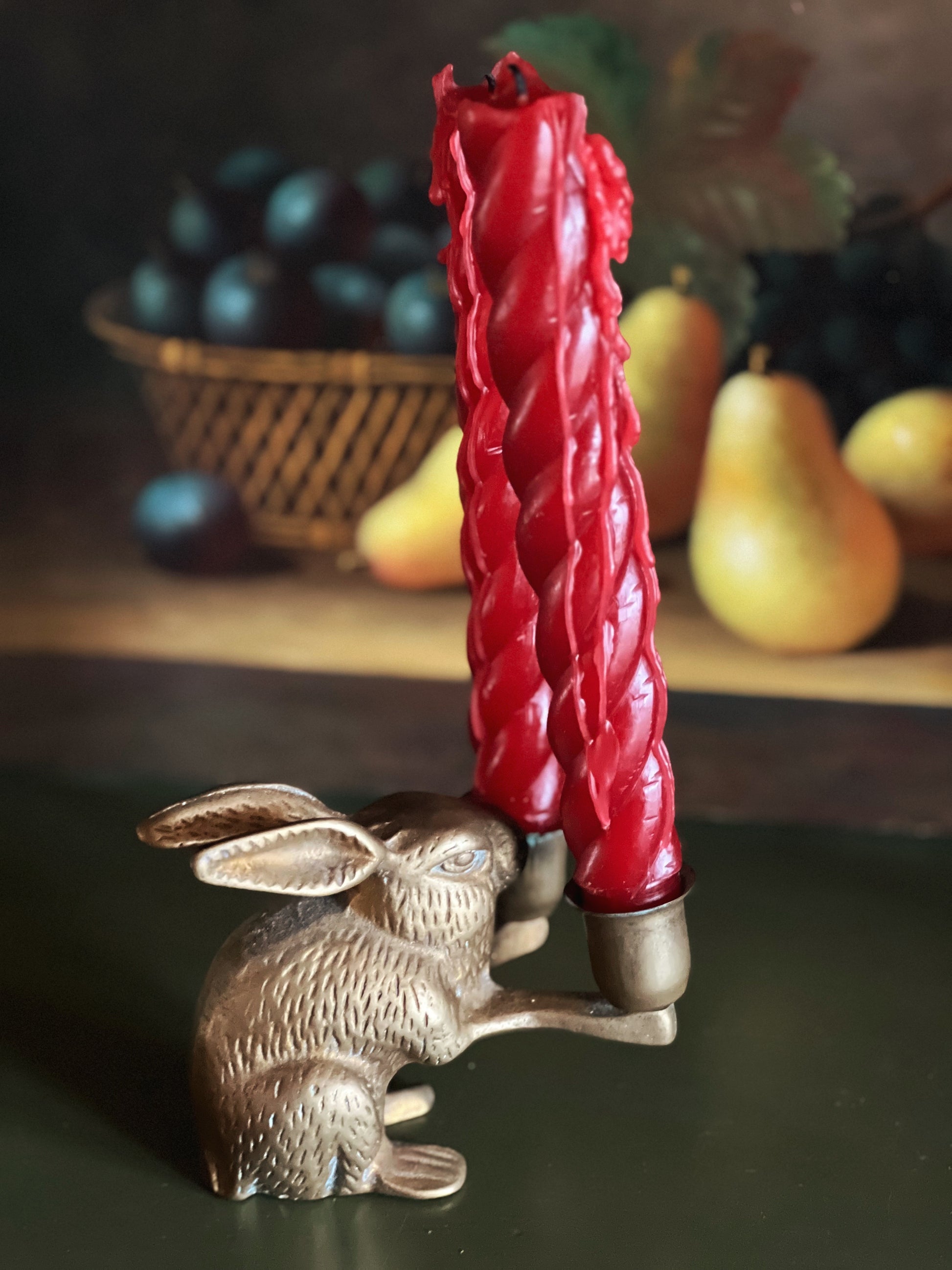 Decorative candle holder shaped like a rabbit with a red candle on a dark surface.