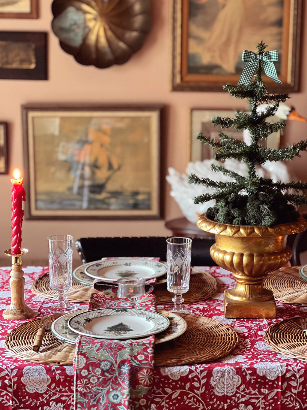 Decorative Christmas table setting with a small tree, candles, and patterned tablecloth.