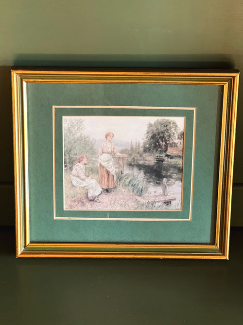 Framed artwork of two people by a pond on a green background