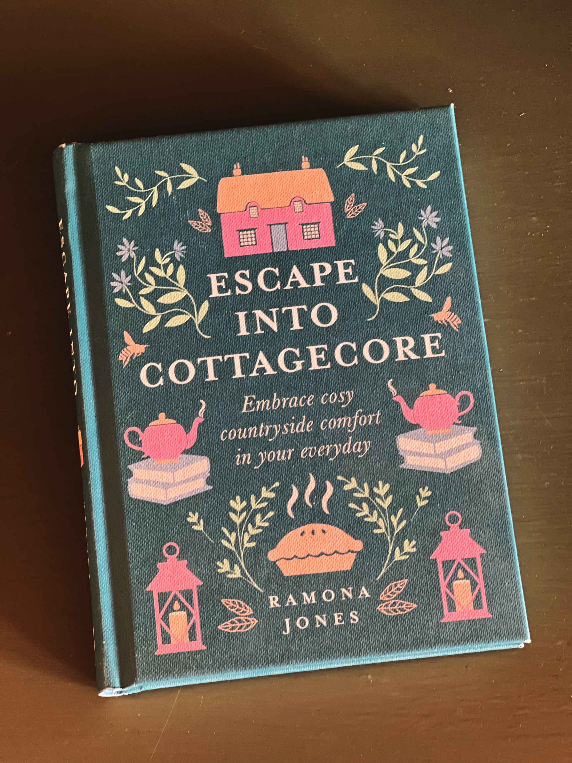 Book titled 'Escape into Cottagecore' by Ramona Jones on a wooden surface