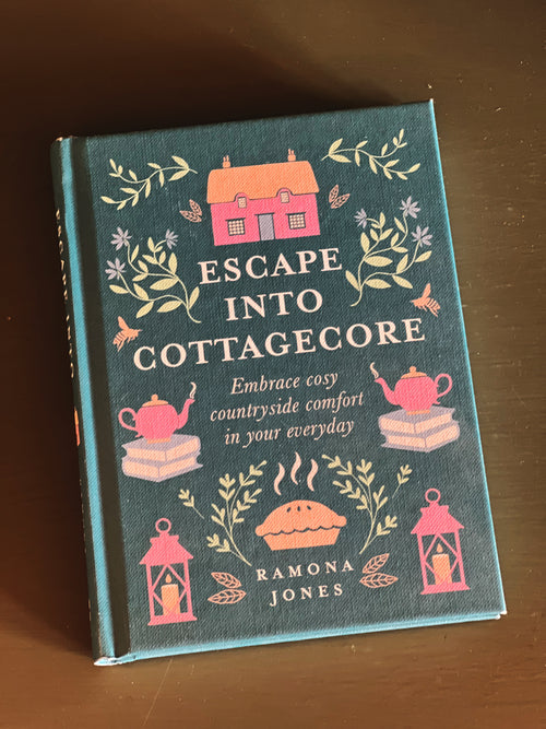 Book titled 'Escape into Cottagecore' by Ramona Jones on a wooden surface