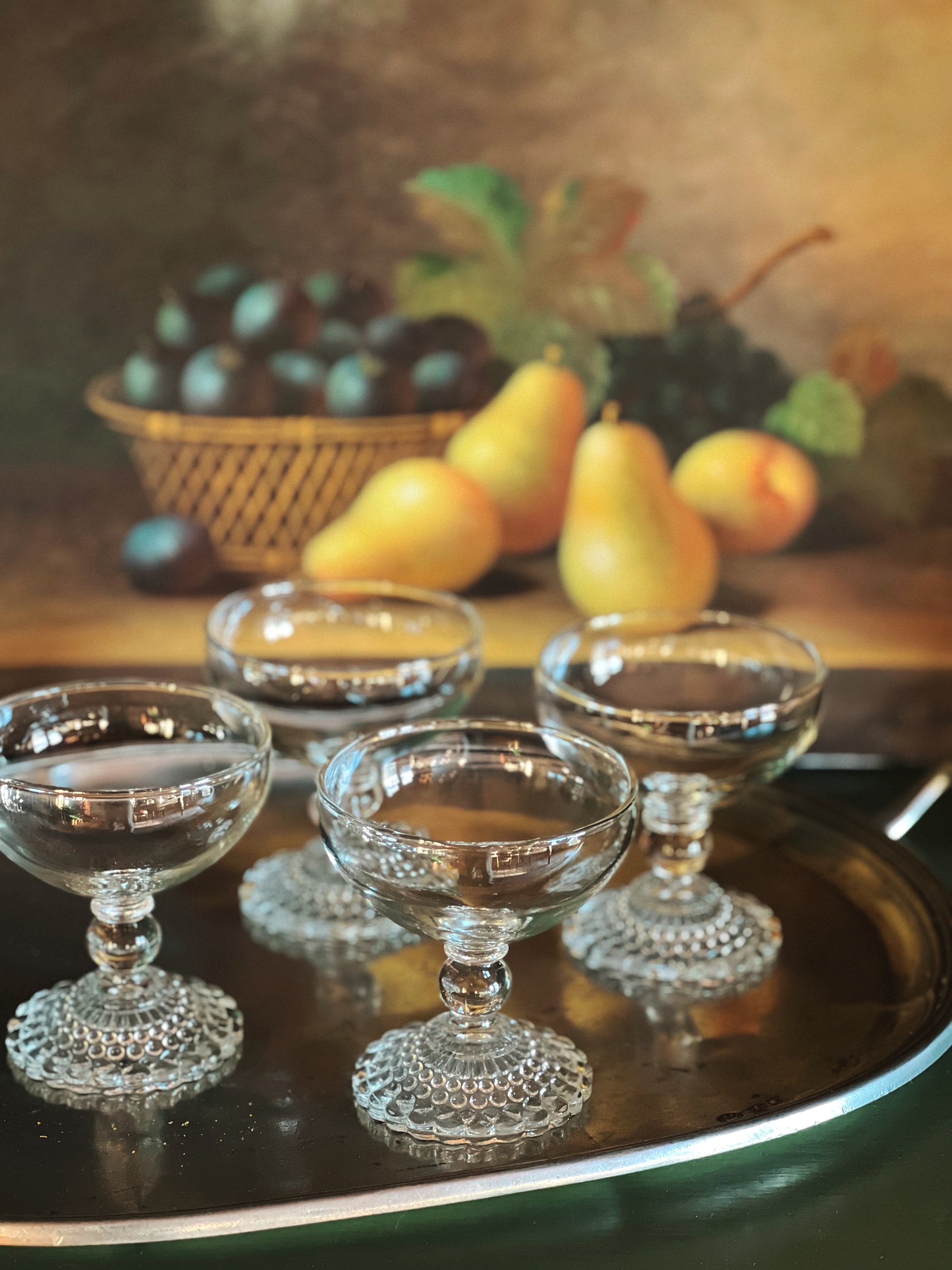 Clear glass dessert dishes on a dark surface with fruit in the background