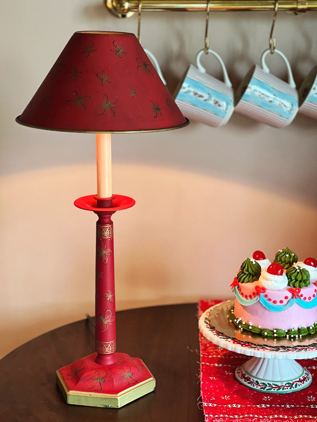 Red lamp with star pattern next to a cake on a table.