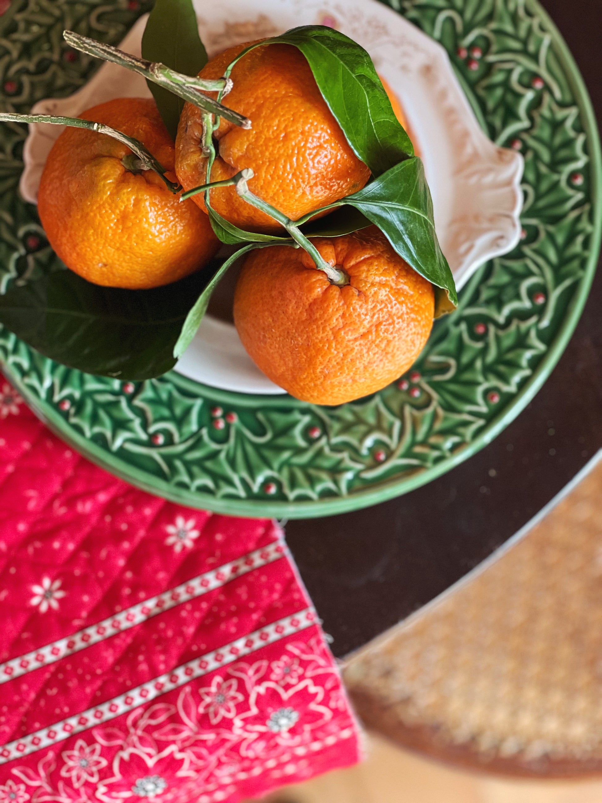 Three mandarins with leaves on a green decorative plate