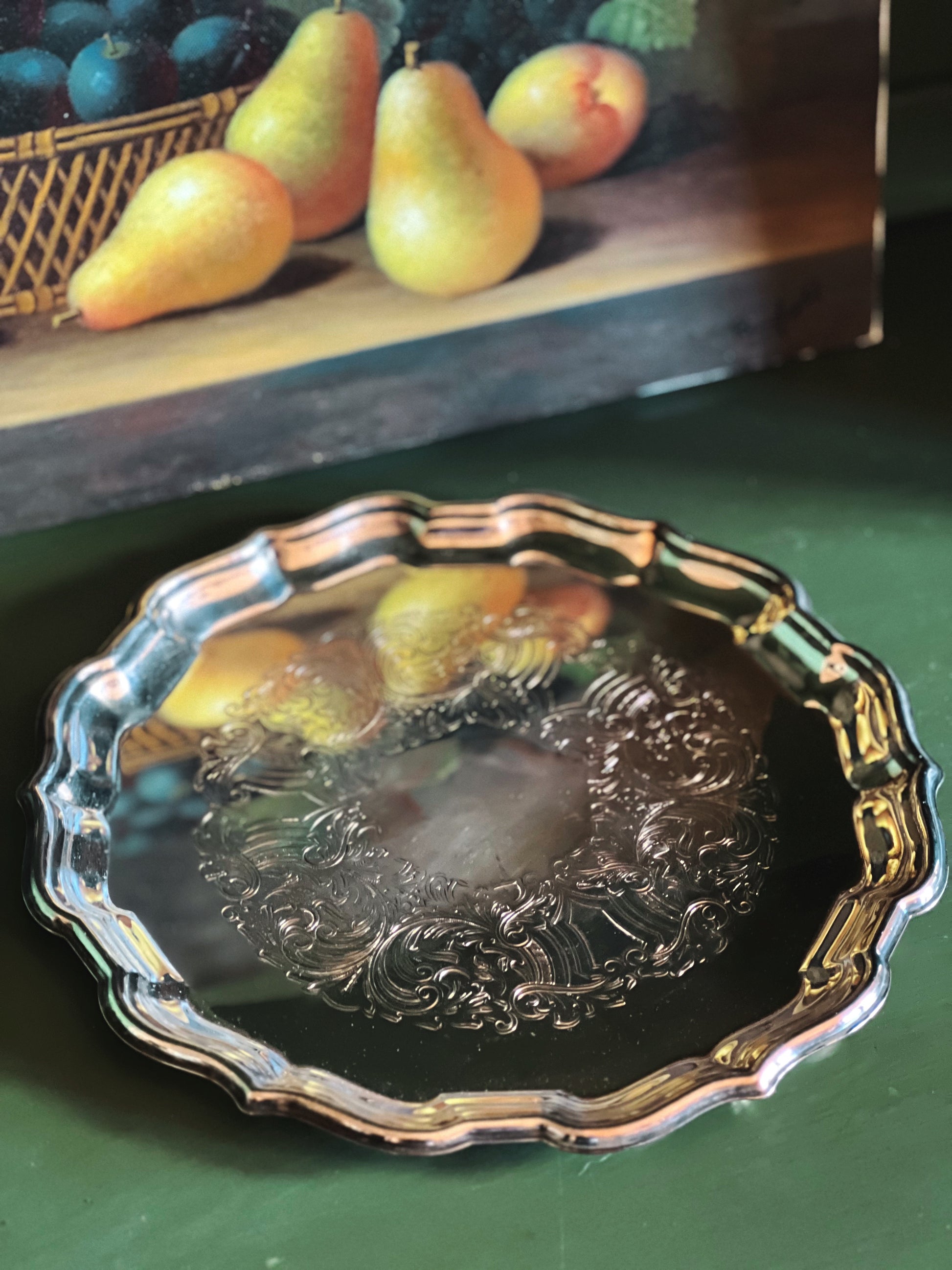 Decorative silver plate with fruit design on a green surface