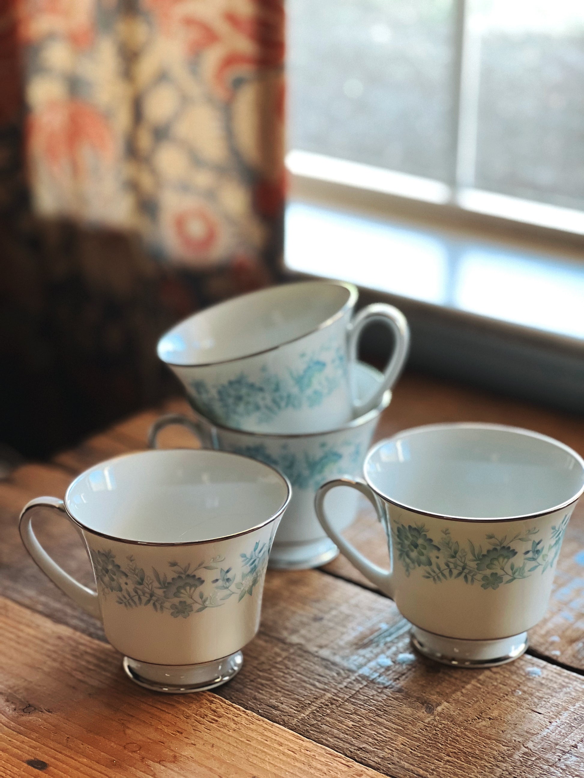 Three floral-patterned cups on a wooden surface with a blurred background
