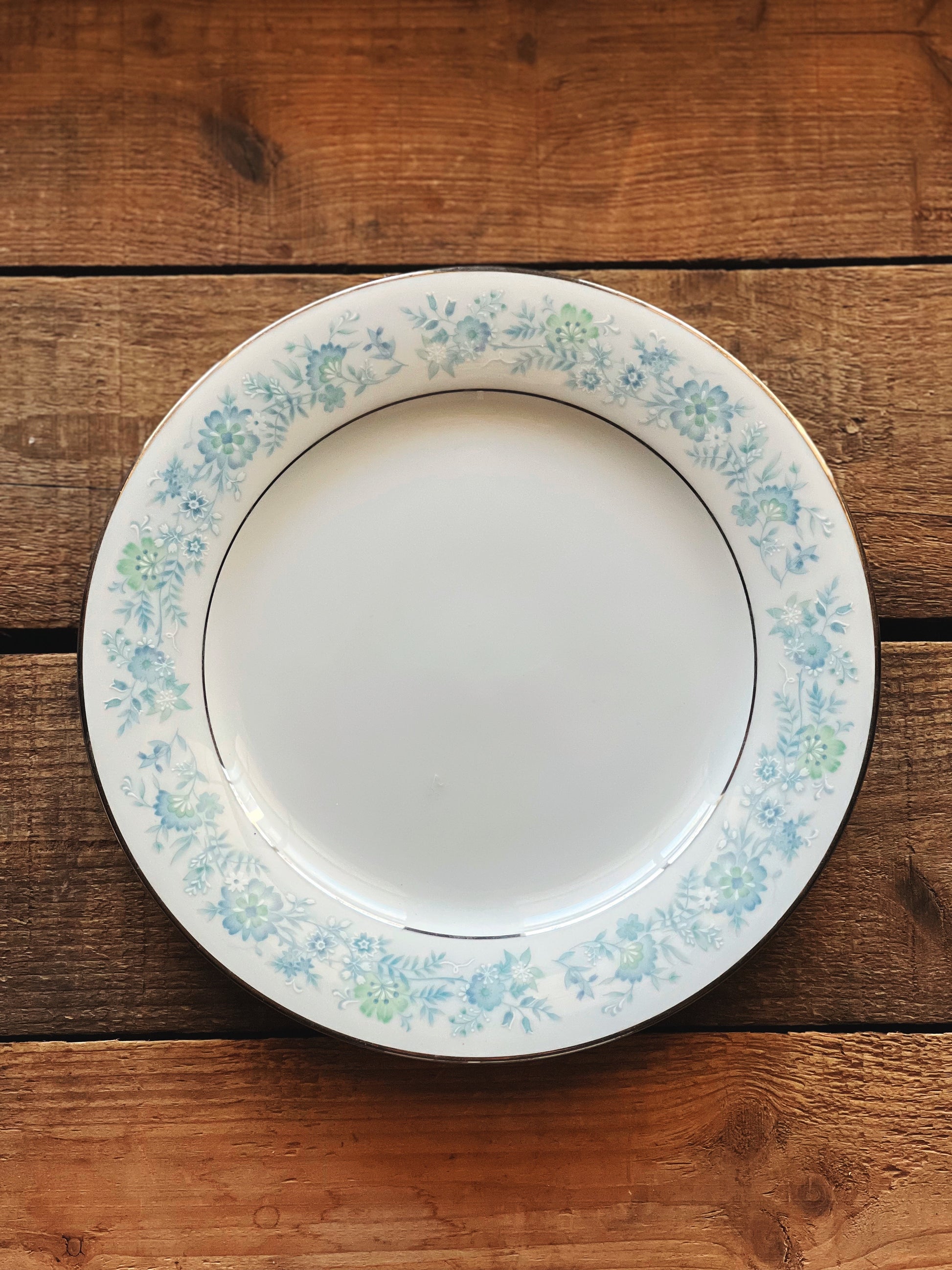 White plate with floral rim on a wooden surface