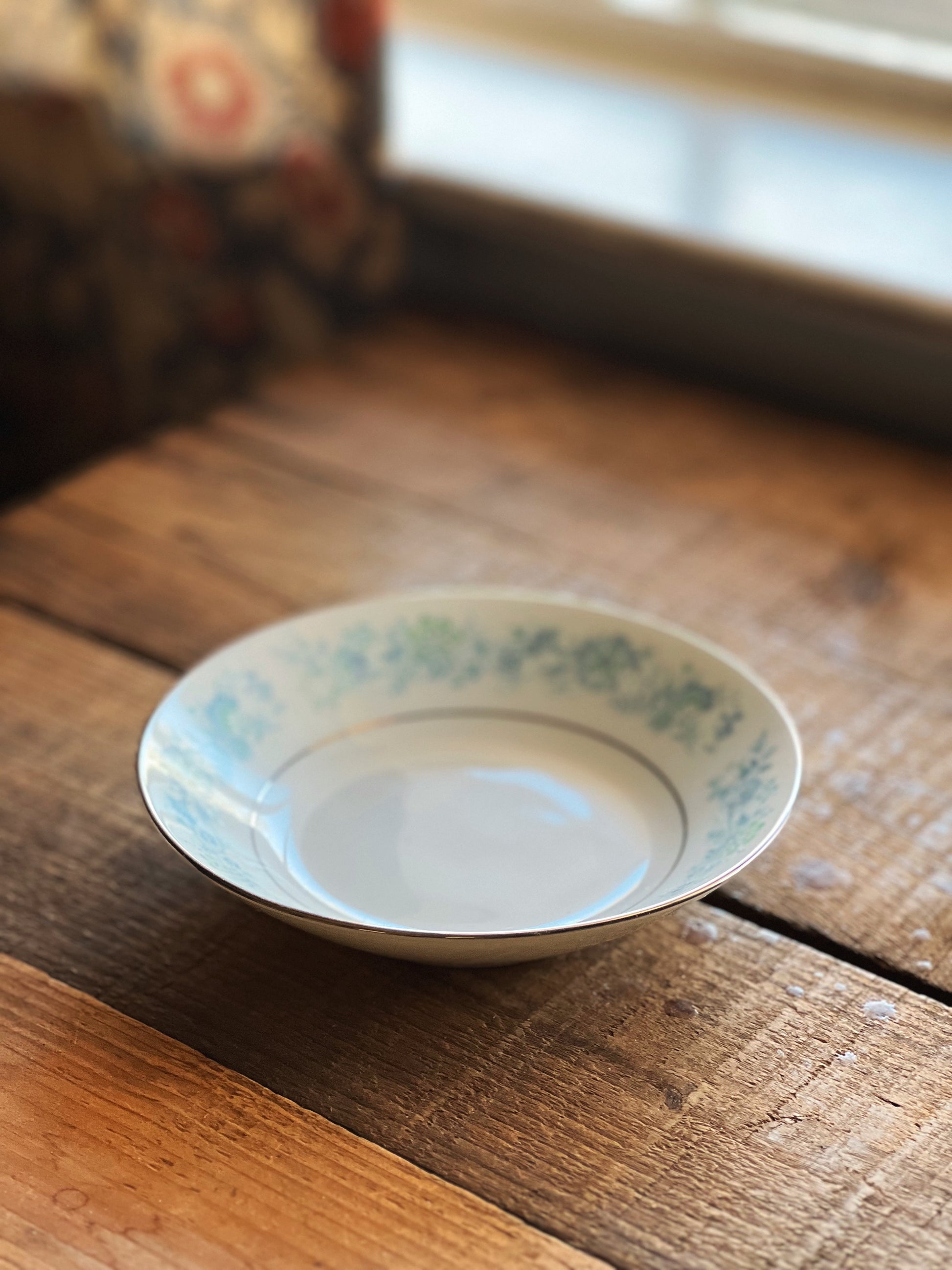 White ceramic plate with green floral pattern on a wooden surface