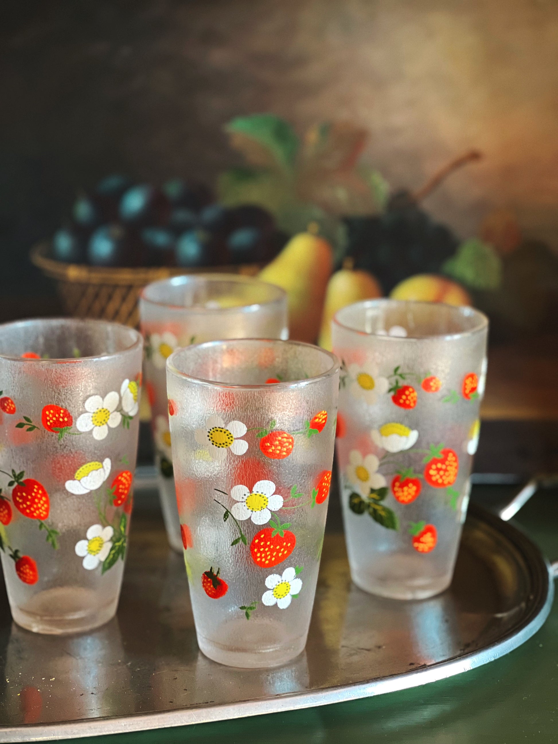 Set of four plastic glasses with fruit and flower patterns on a metal tray.