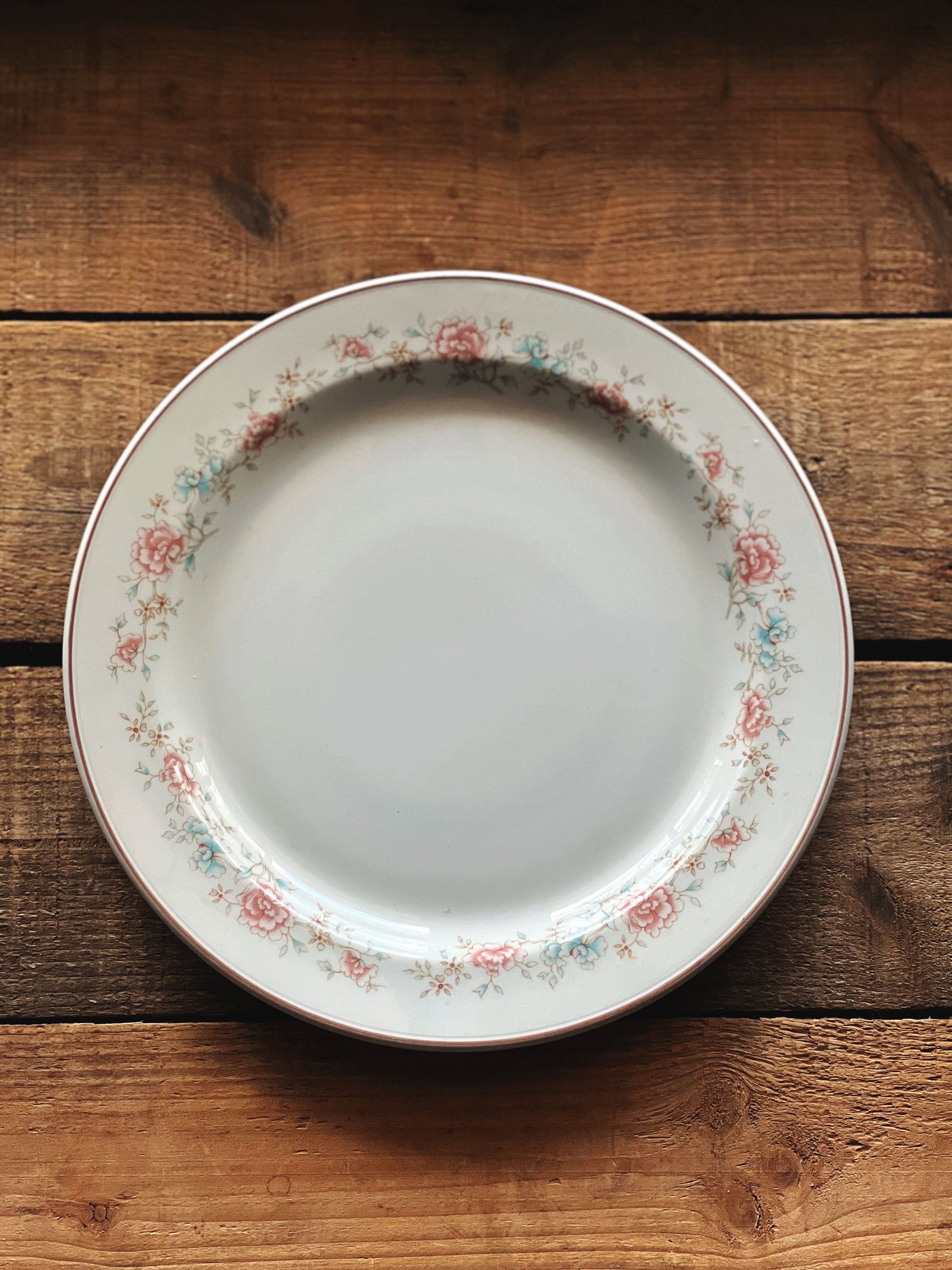 Decorative plate with floral rim on a wooden surface