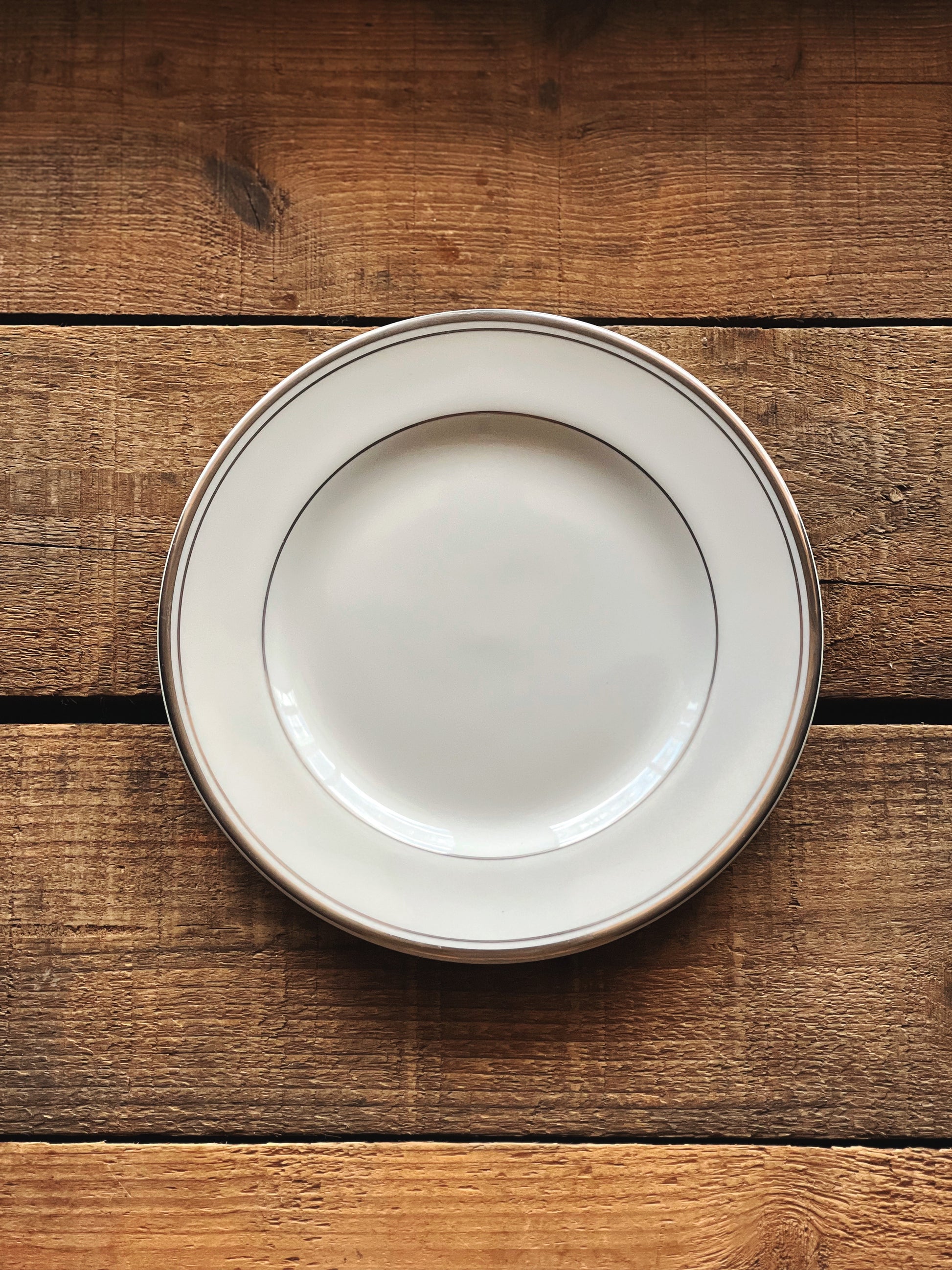 White ceramic plate with a gold rim on a wooden surface