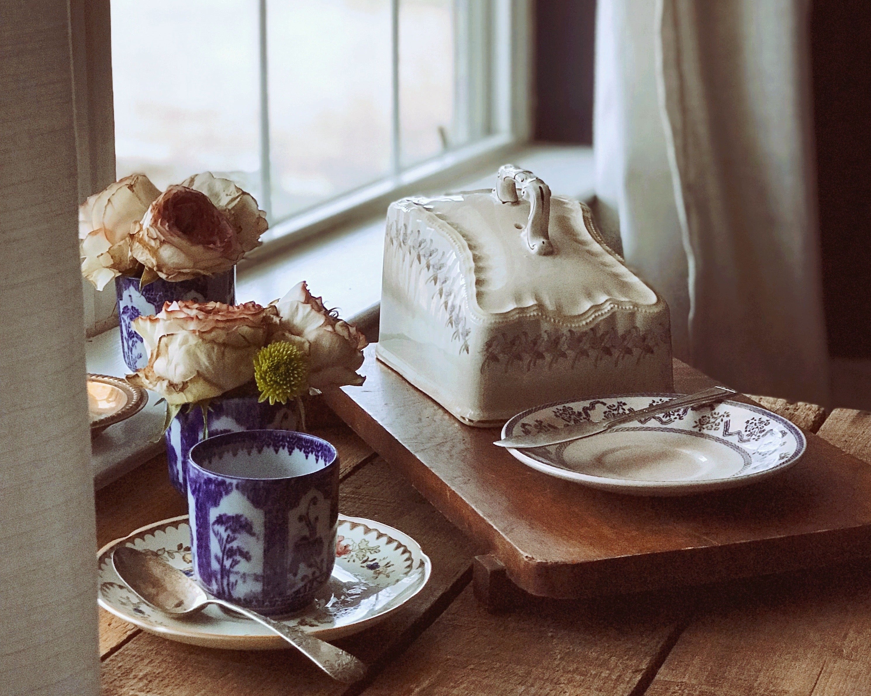 Tea set on a wooden table with a window in the background