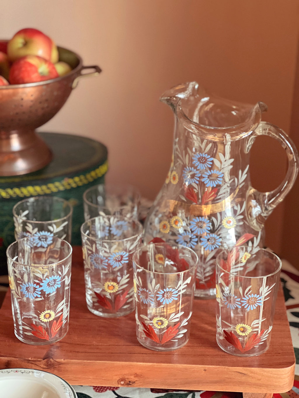 Set of floral-patterned glassware including a pitcher and tumblers on a wooden surface.