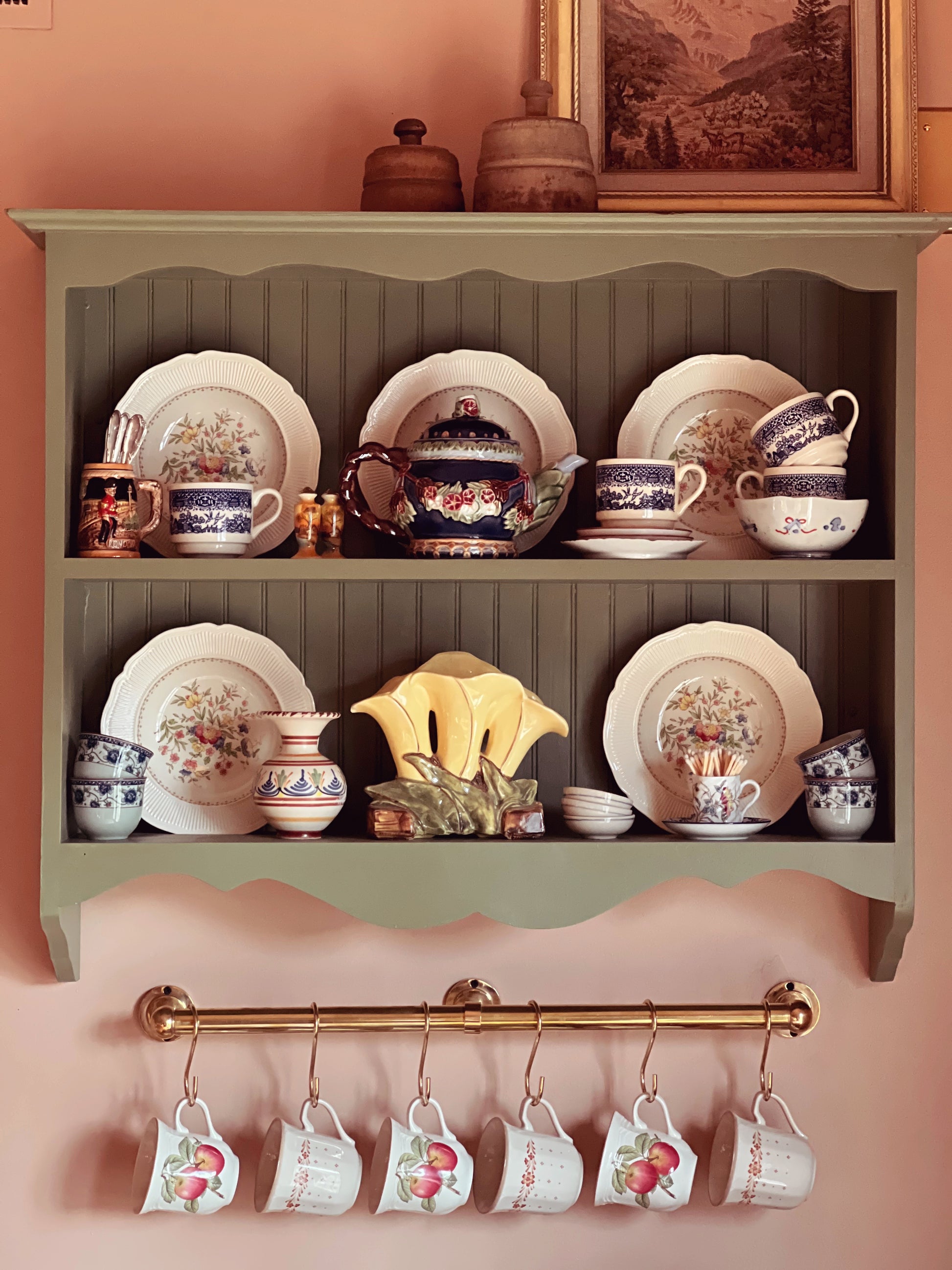 Shelf with decorative plates and teacups, and hanging teacups below.