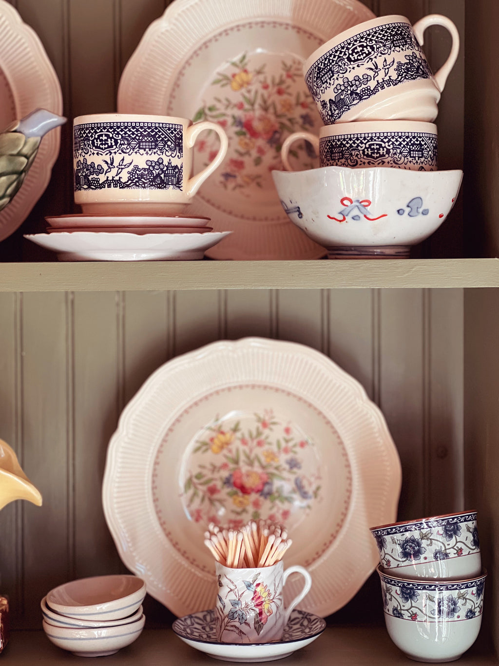 Set of ceramic dishes with floral patterns on a wooden shelf.