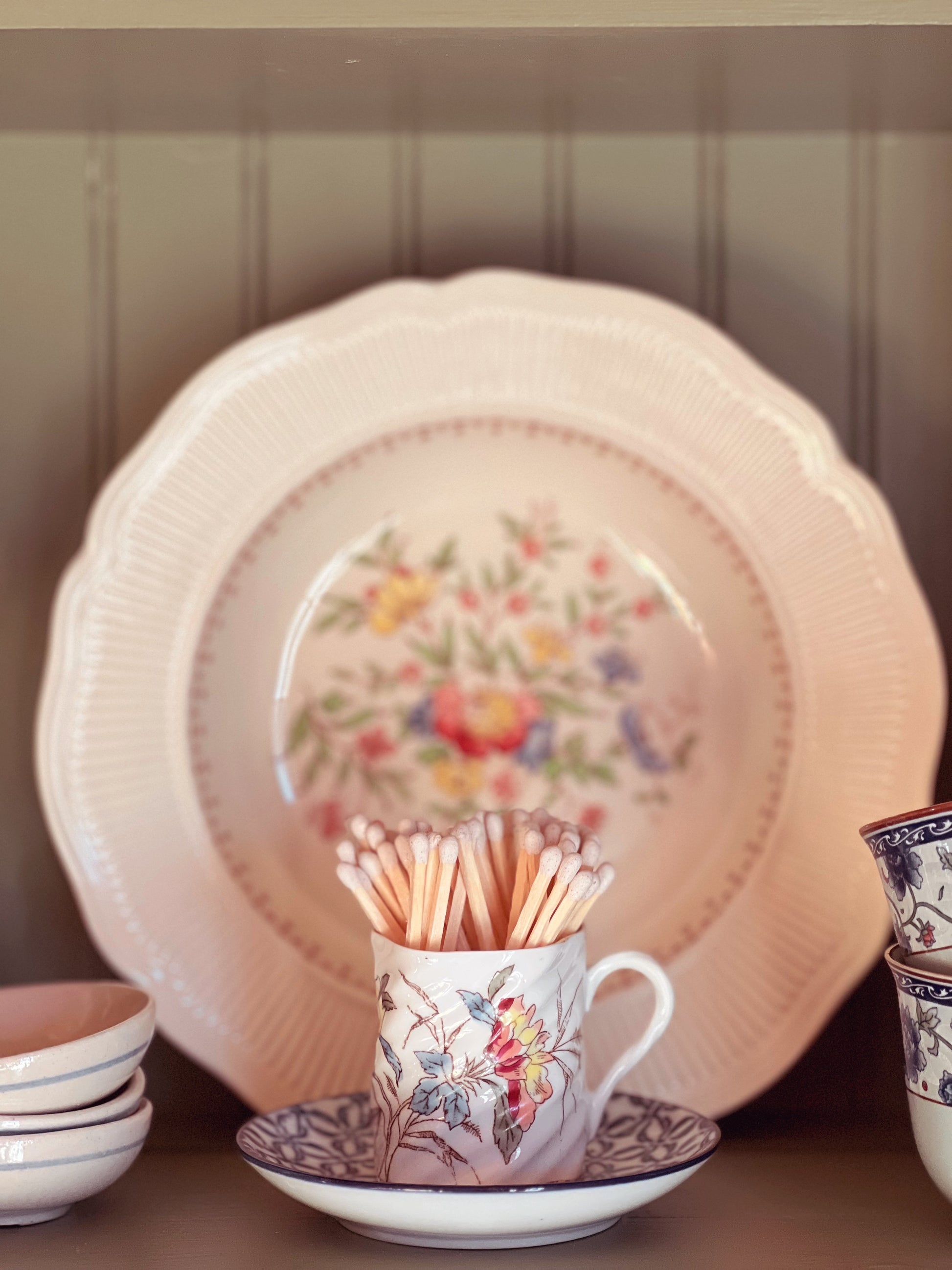 Floral-patterned ceramic plates and cups on a wooden surface with a neutral background