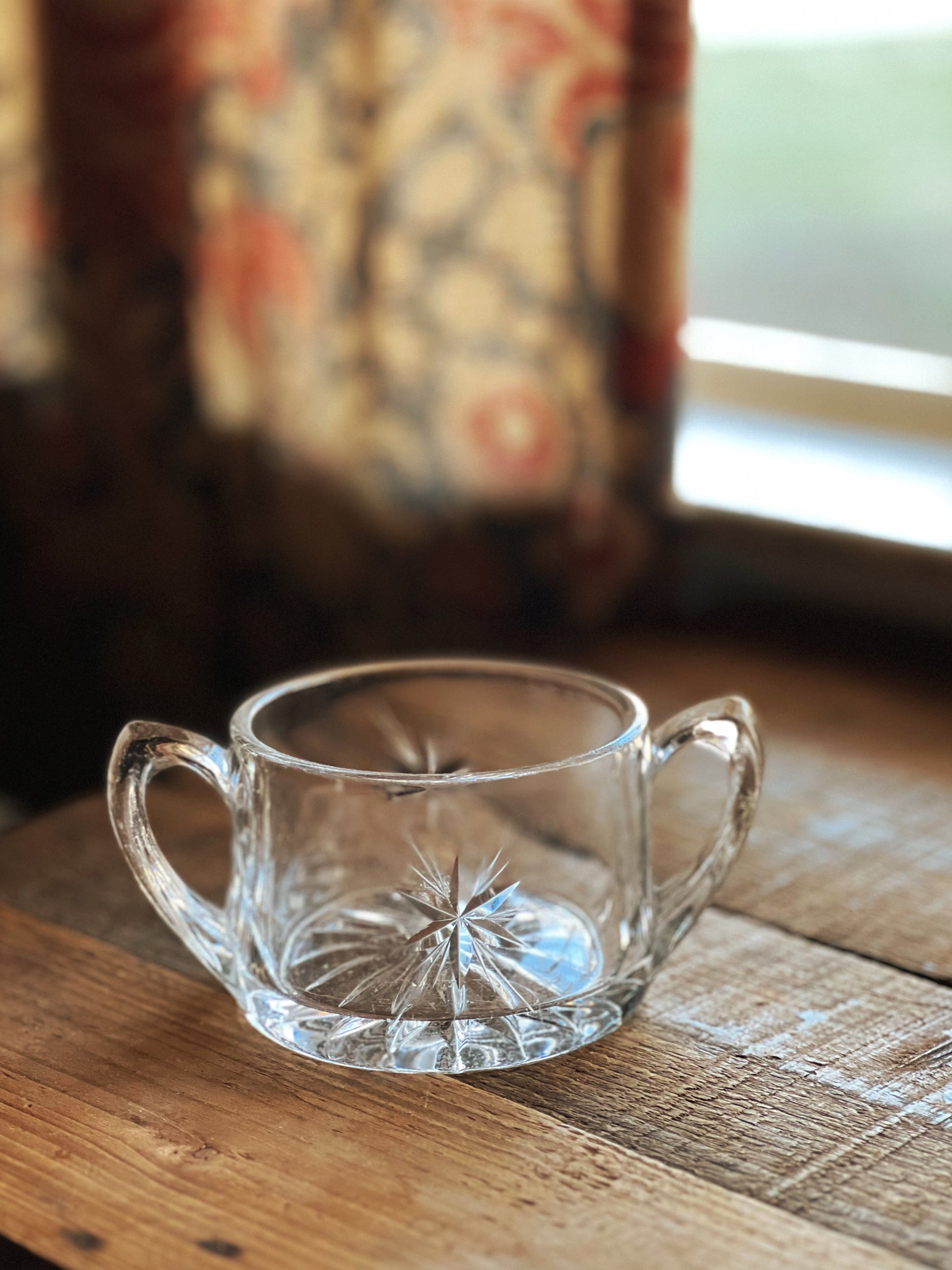 Clear glass teacup with handles on a wooden surface