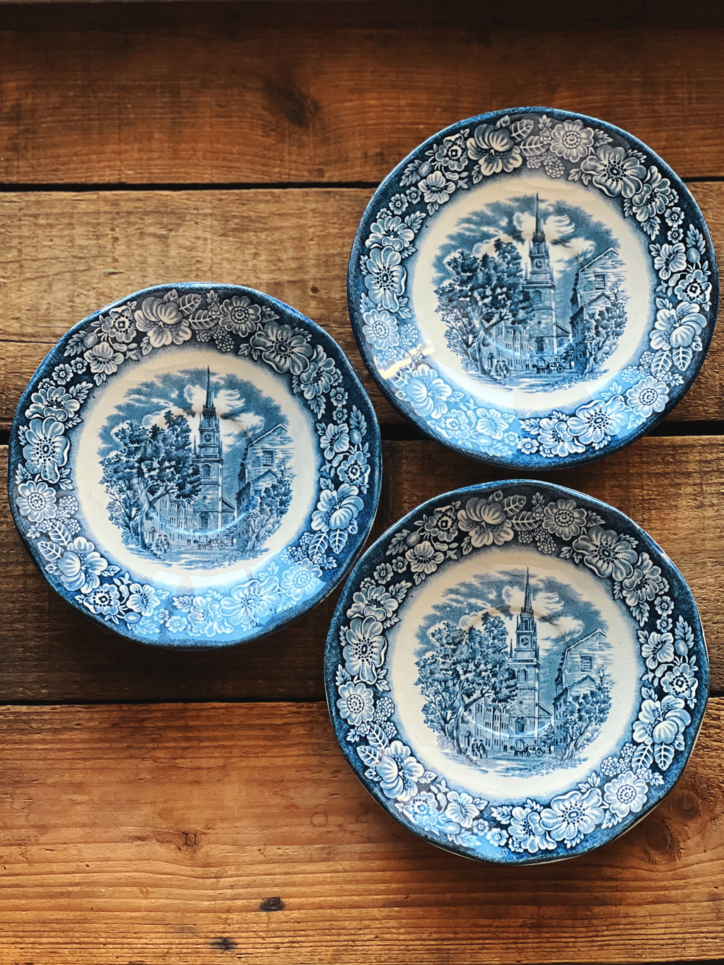Three blue and white decorative plates on a wooden surface