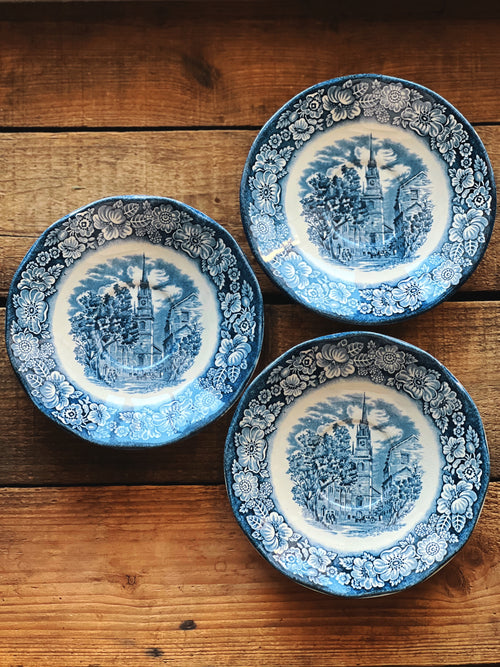 Three blue and white decorative plates on a wooden surface