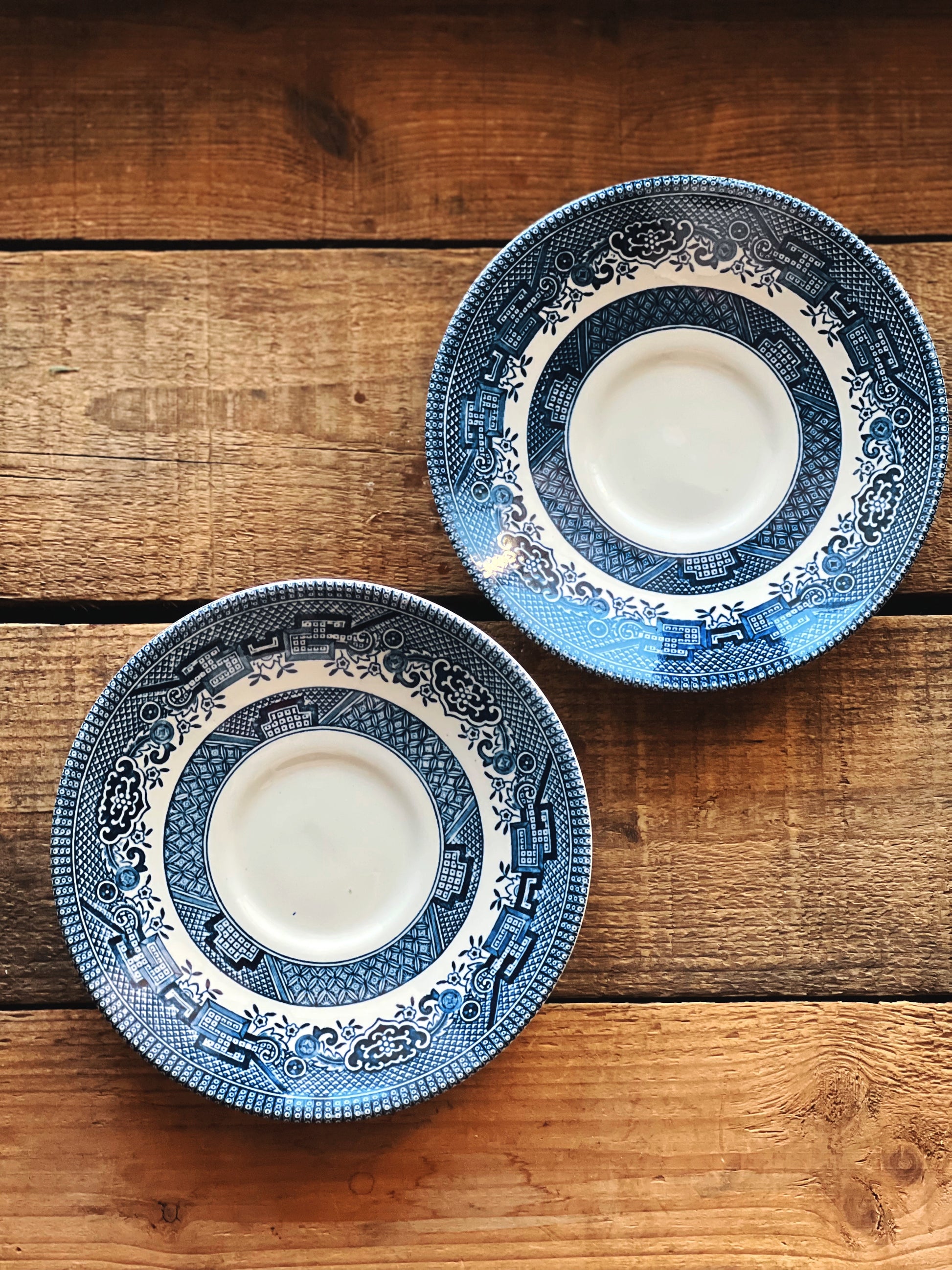 Two blue and white ceramic plates on a wooden surface