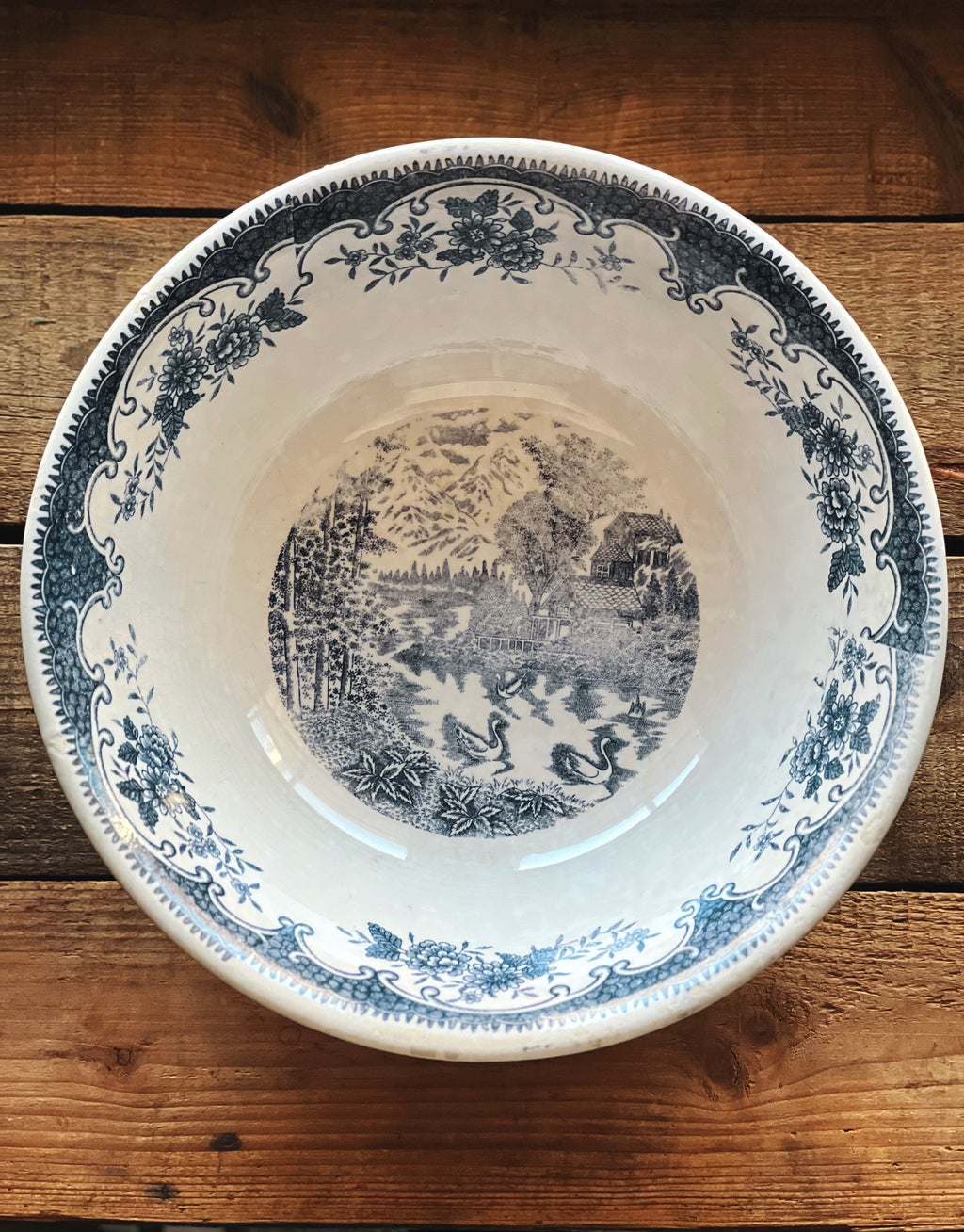 Decorative ceramic plate with blue floral and landscape design on a wooden surface
