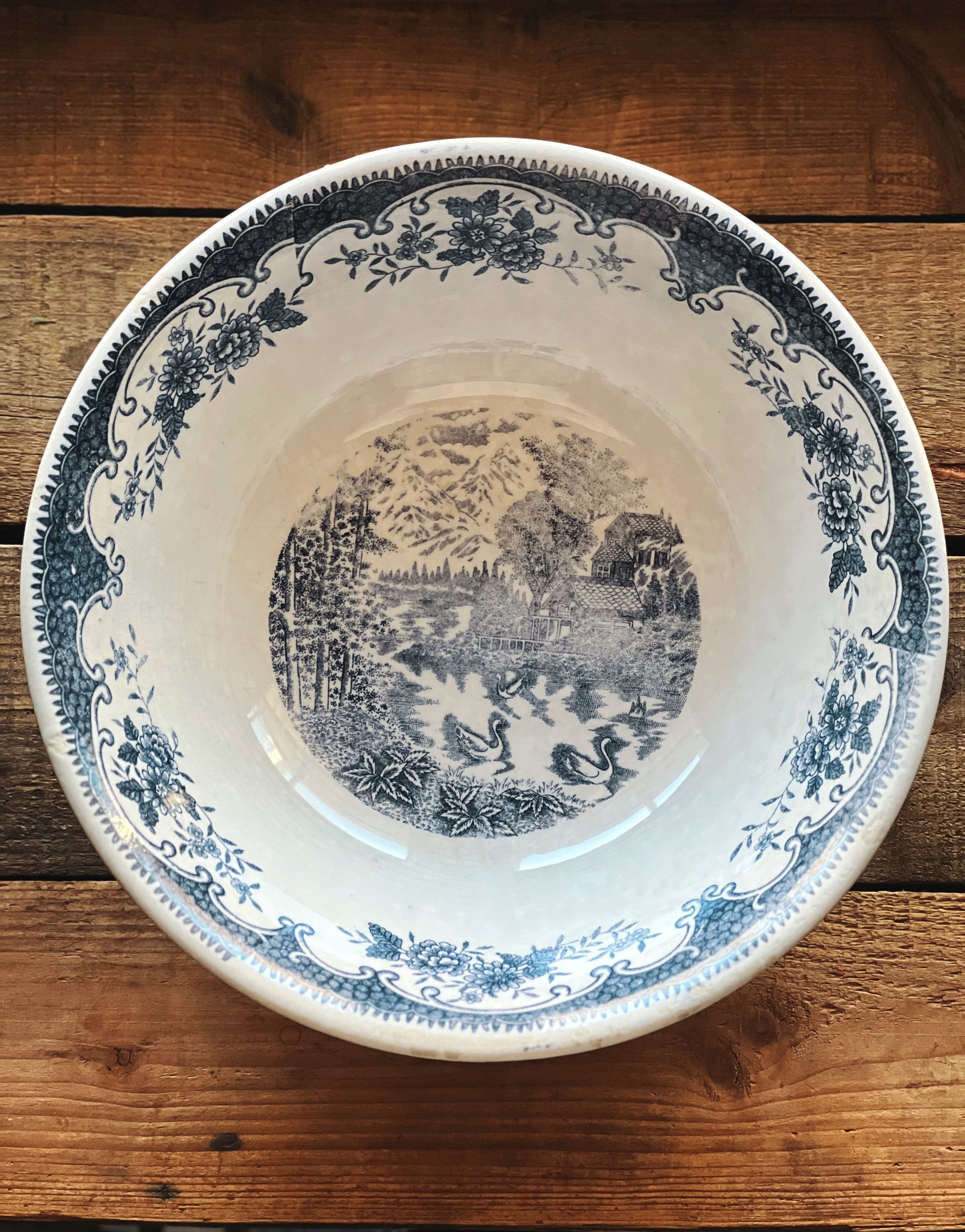 Decorative ceramic plate with blue floral and landscape design on a wooden surface