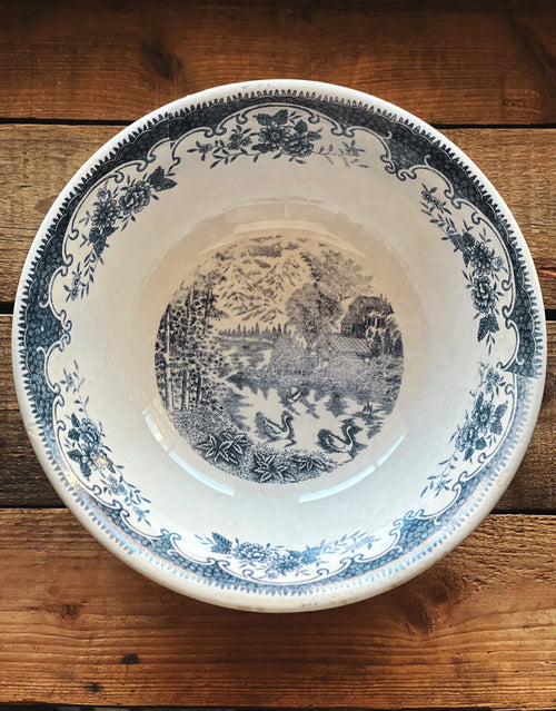 Decorative ceramic plate with blue floral and landscape design on a wooden surface