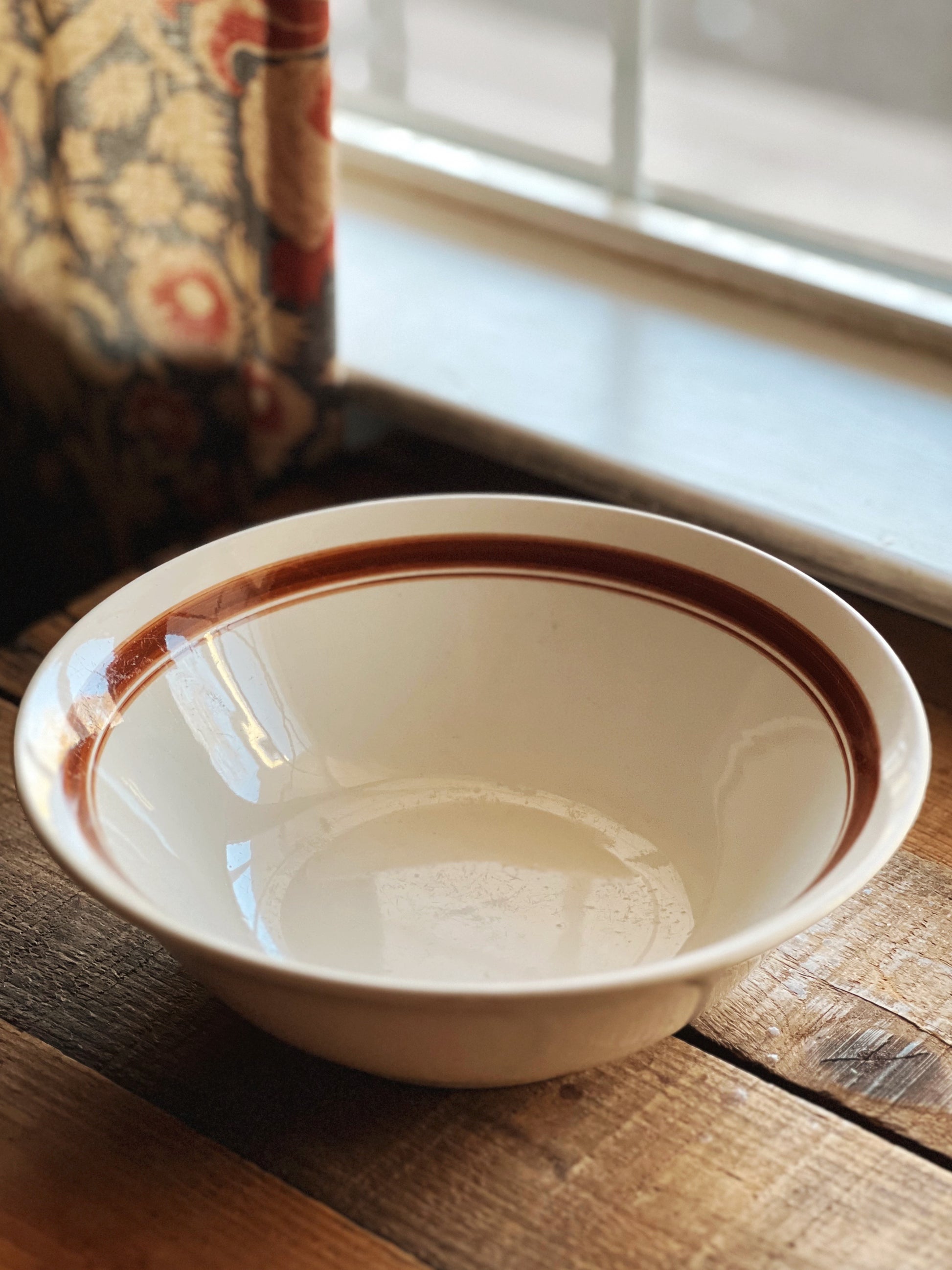 White ceramic bowl with brown rim on a wooden surface