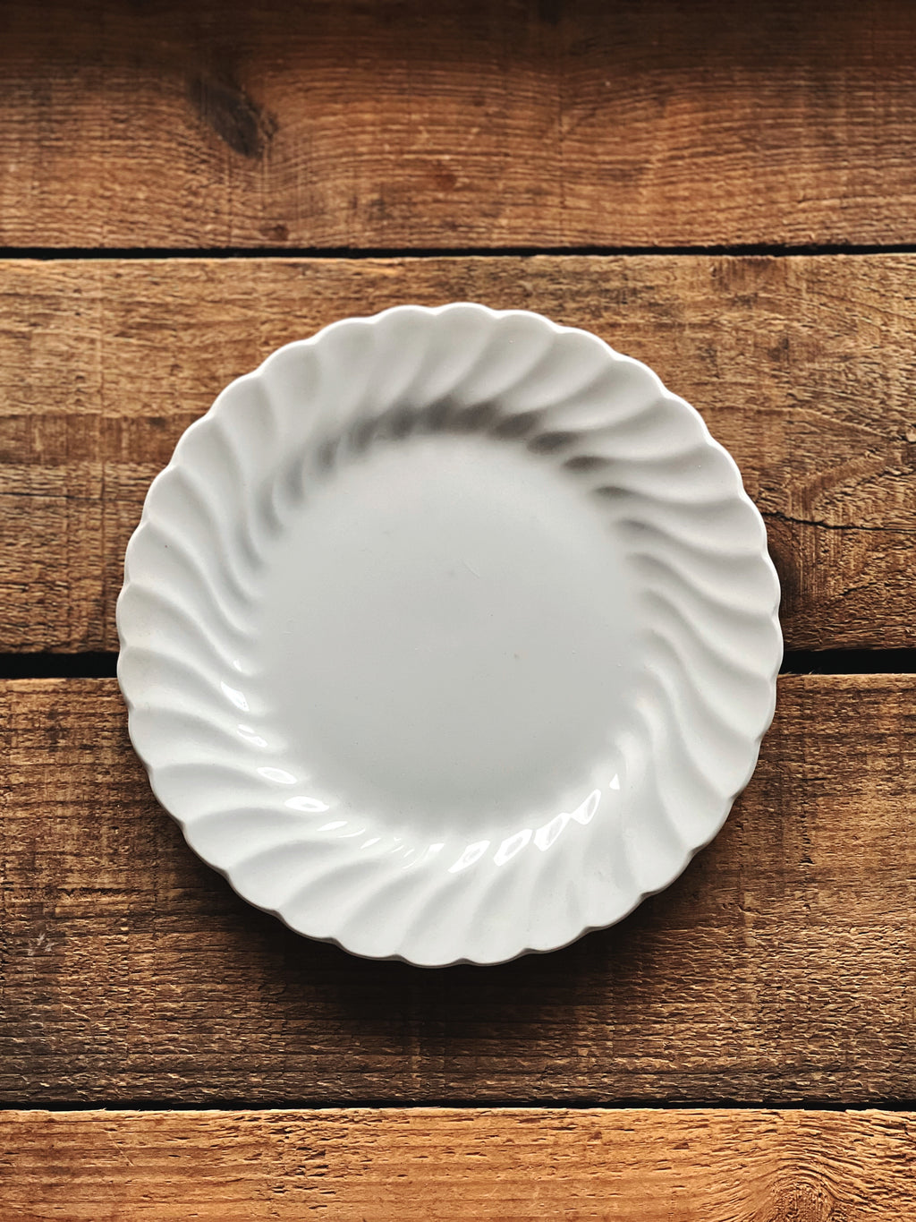 White ceramic plate with scalloped edge on a wooden surface
