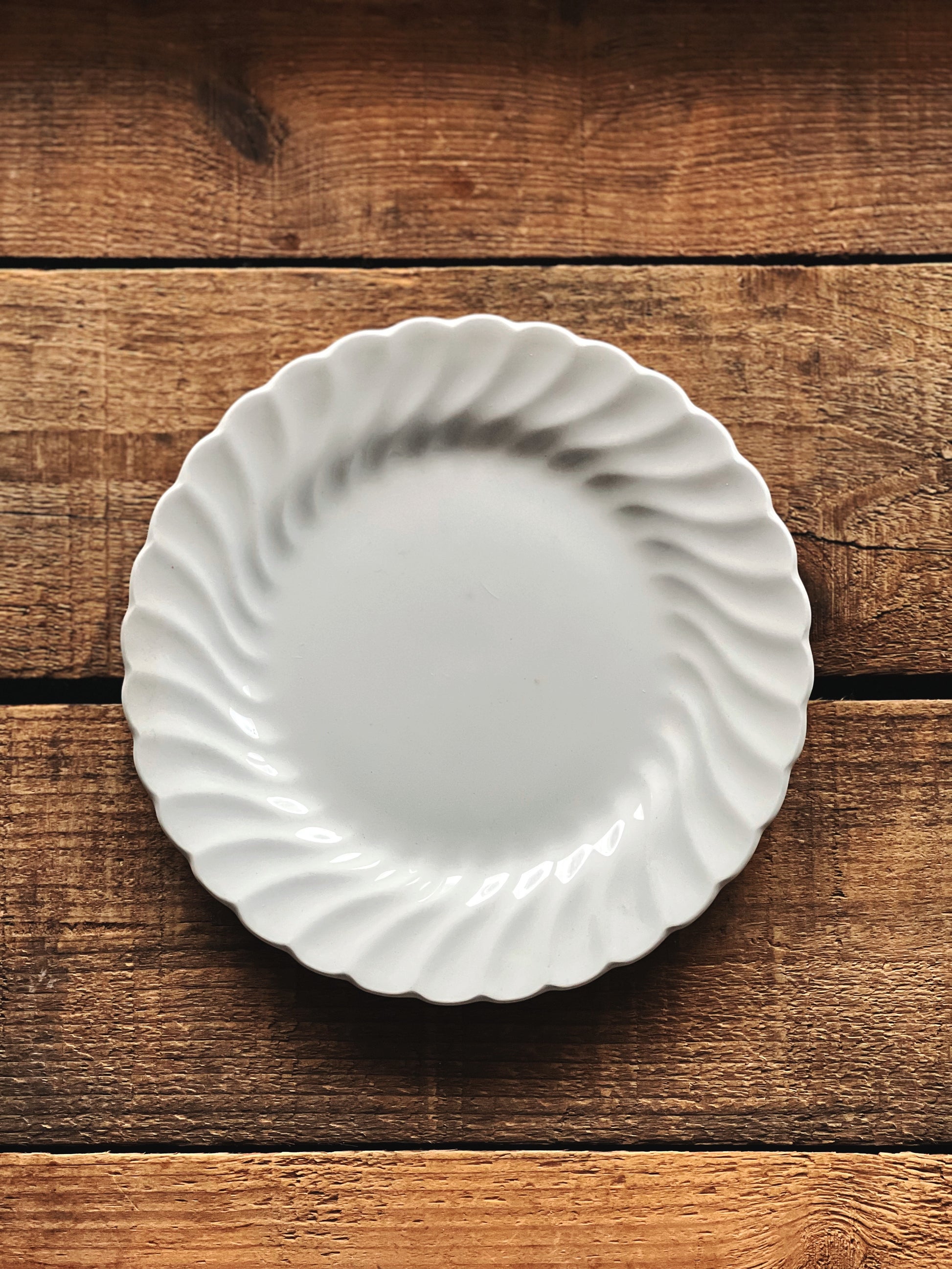 White ceramic plate with scalloped edge on a wooden surface