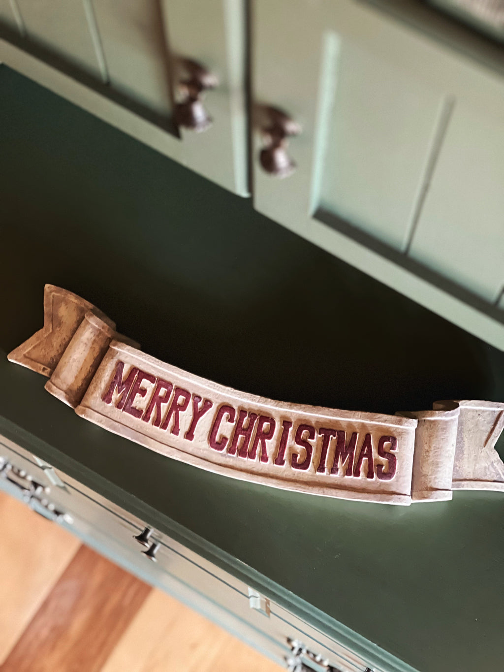 Resin 'Merry Christmas' sign on a green cabinet