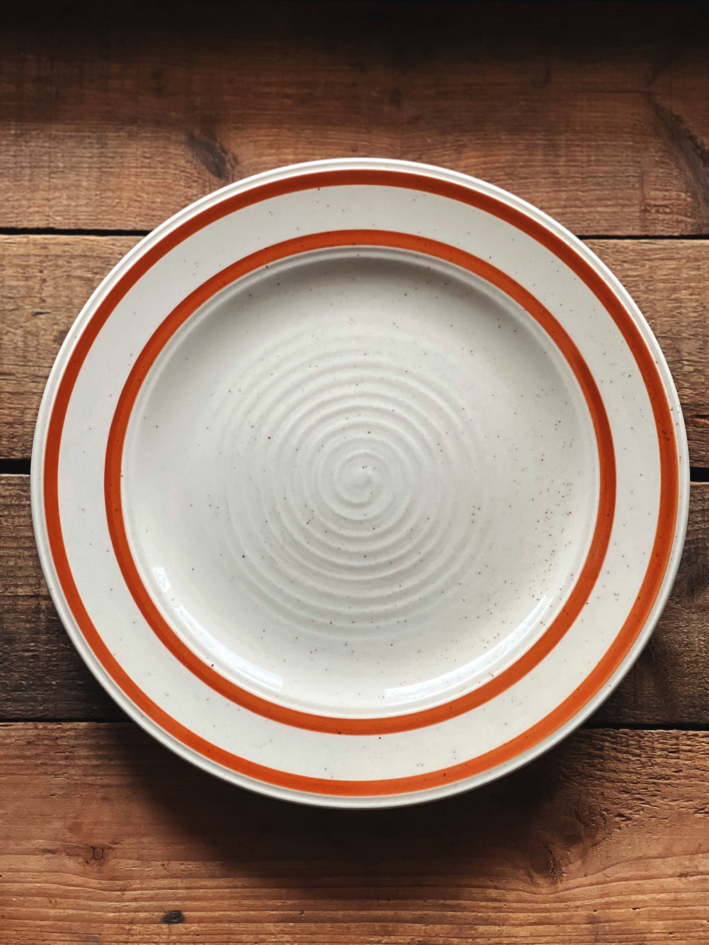 White ceramic plate with orange rim on a wooden surface