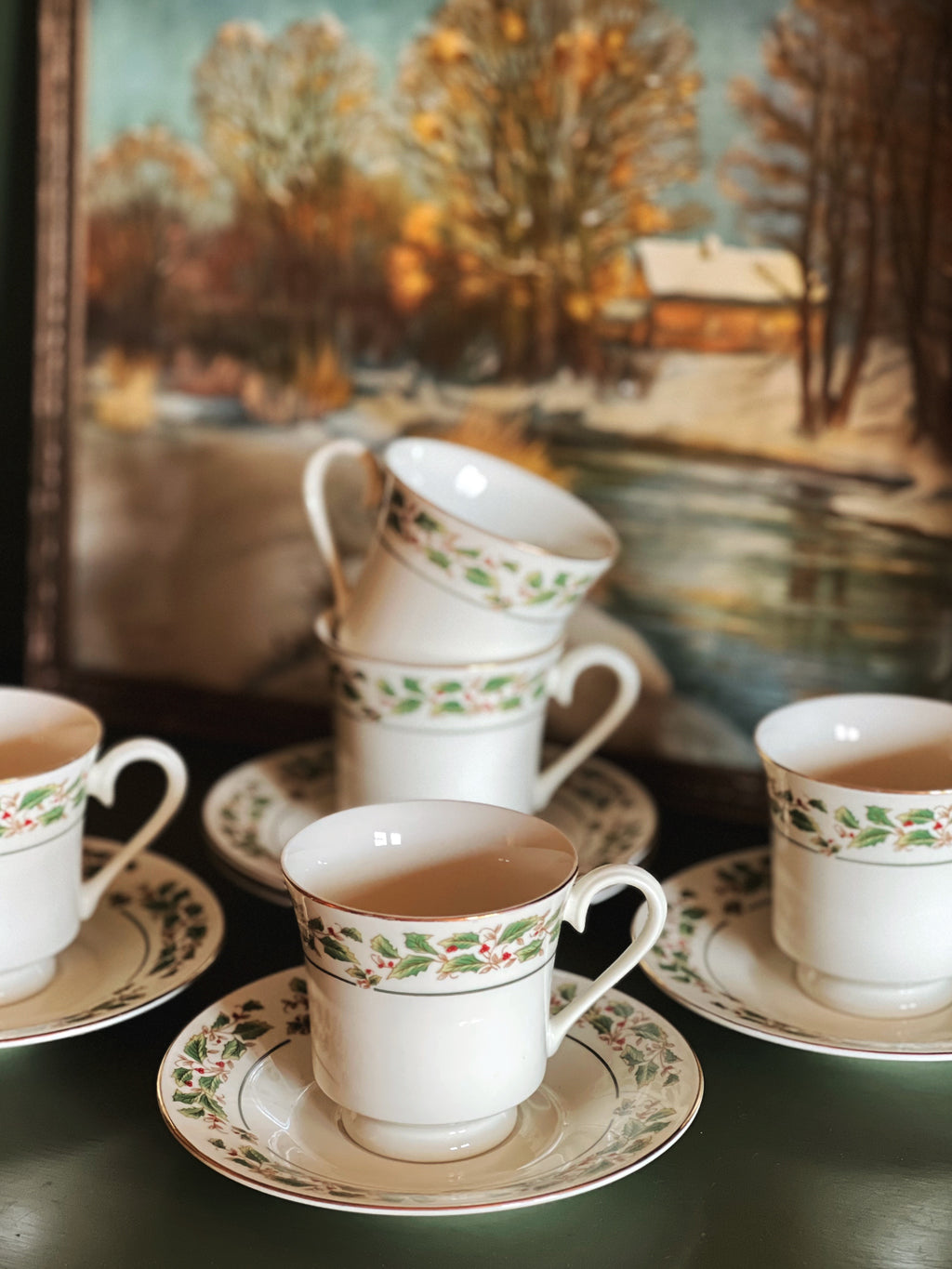 Set of vintage teacups and saucers with a scenic painting in the background