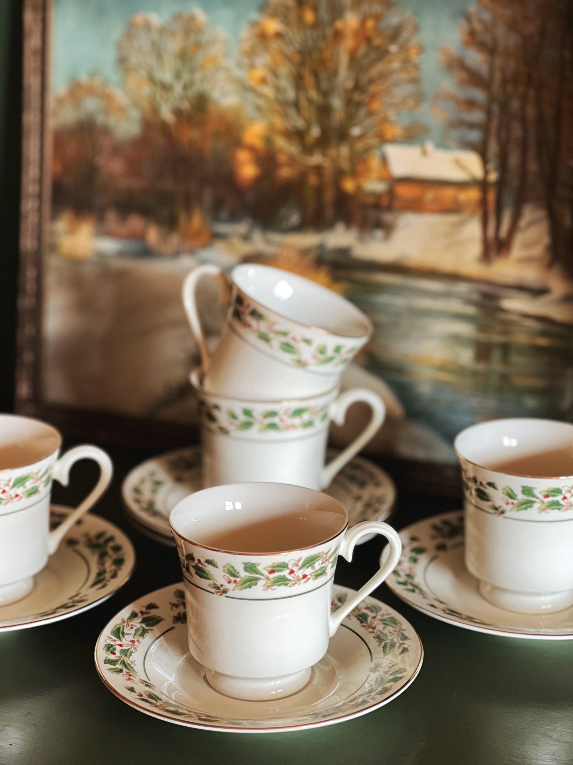 Set of vintage teacups and saucers with a scenic painting in the background