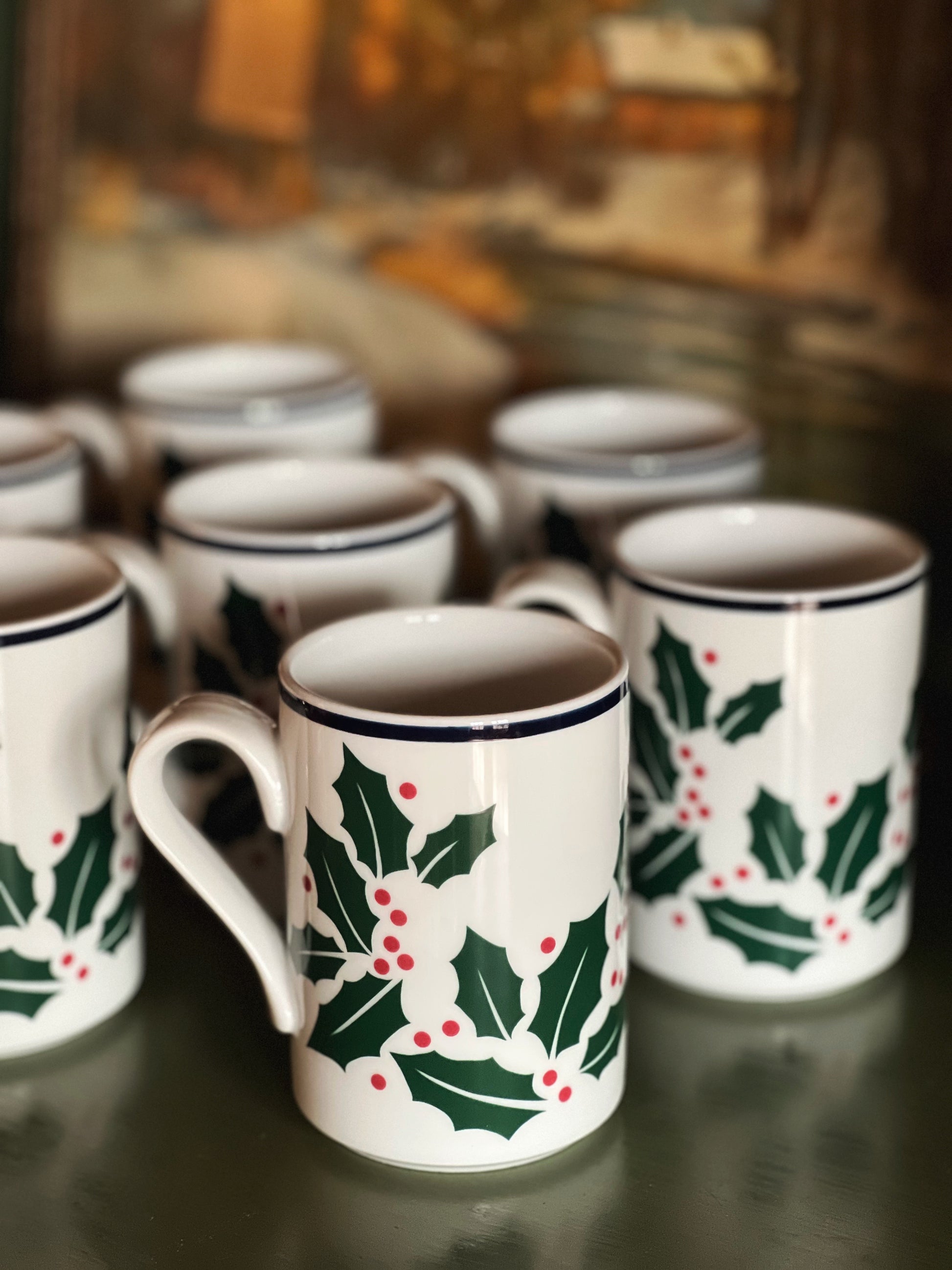Set of mugs with holly design on a reflective surface
