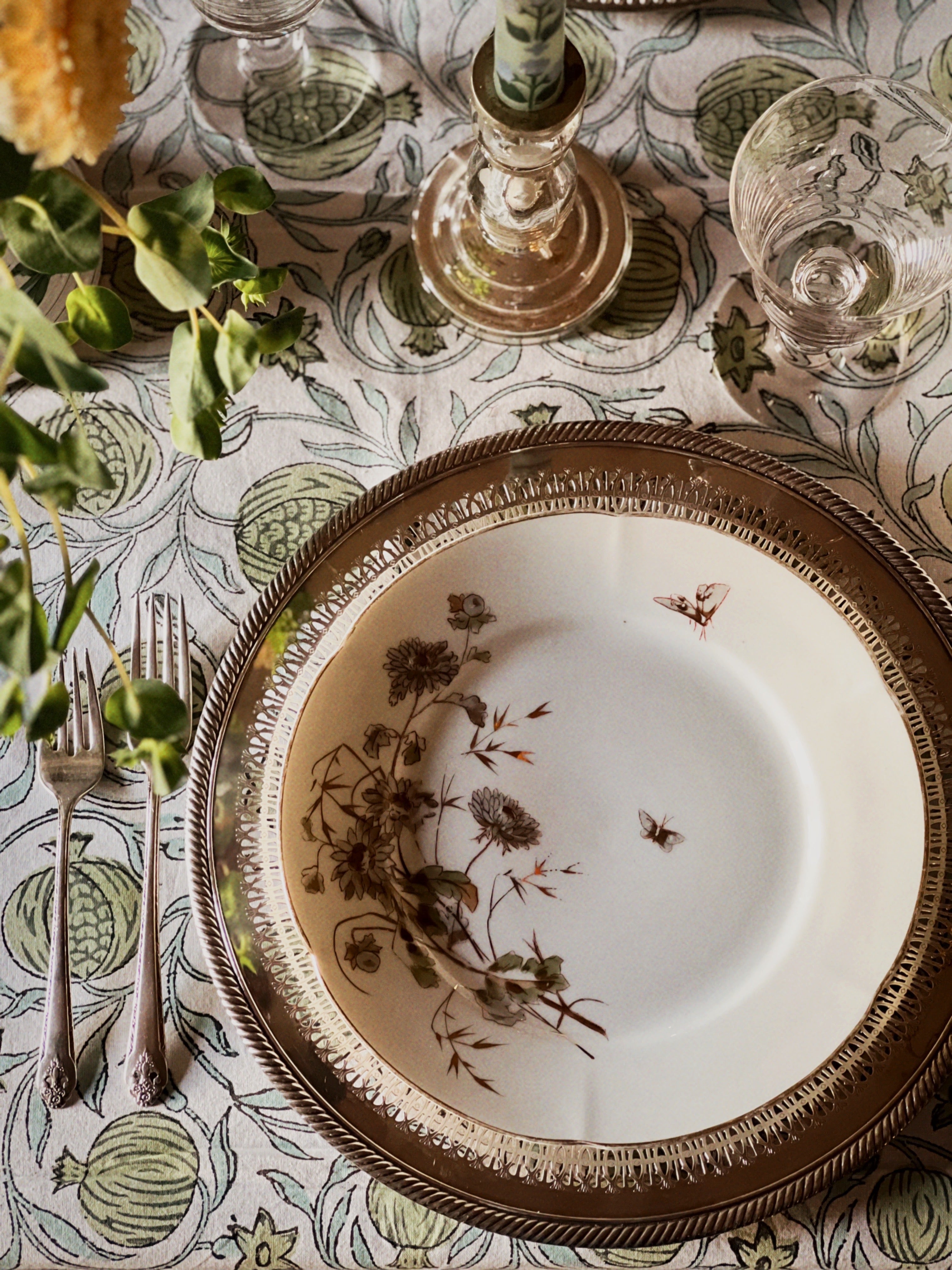 china dinner plate on a silver charger on a table set for dinner 